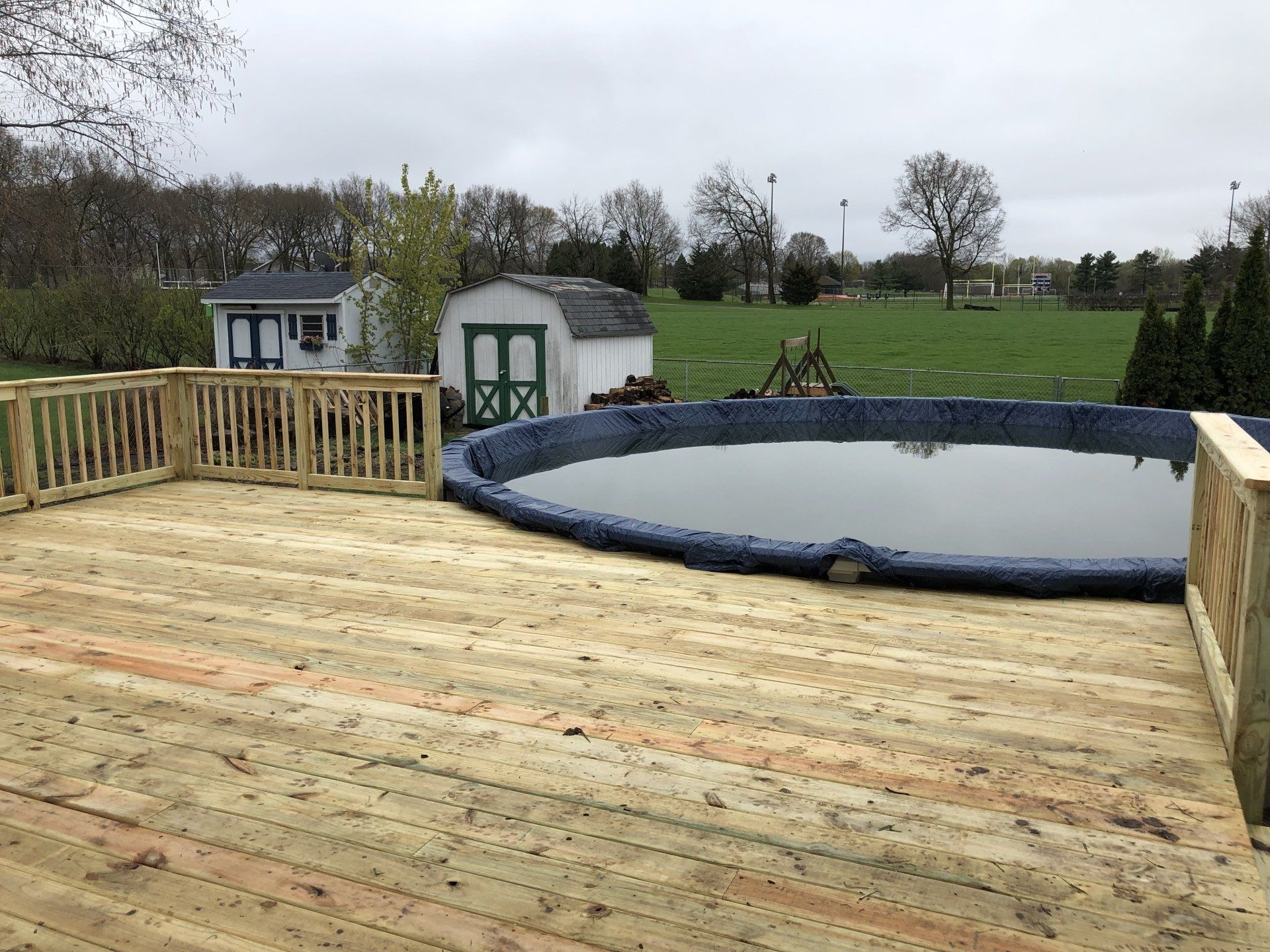 A wooden deck with a large pool in the middle of it.