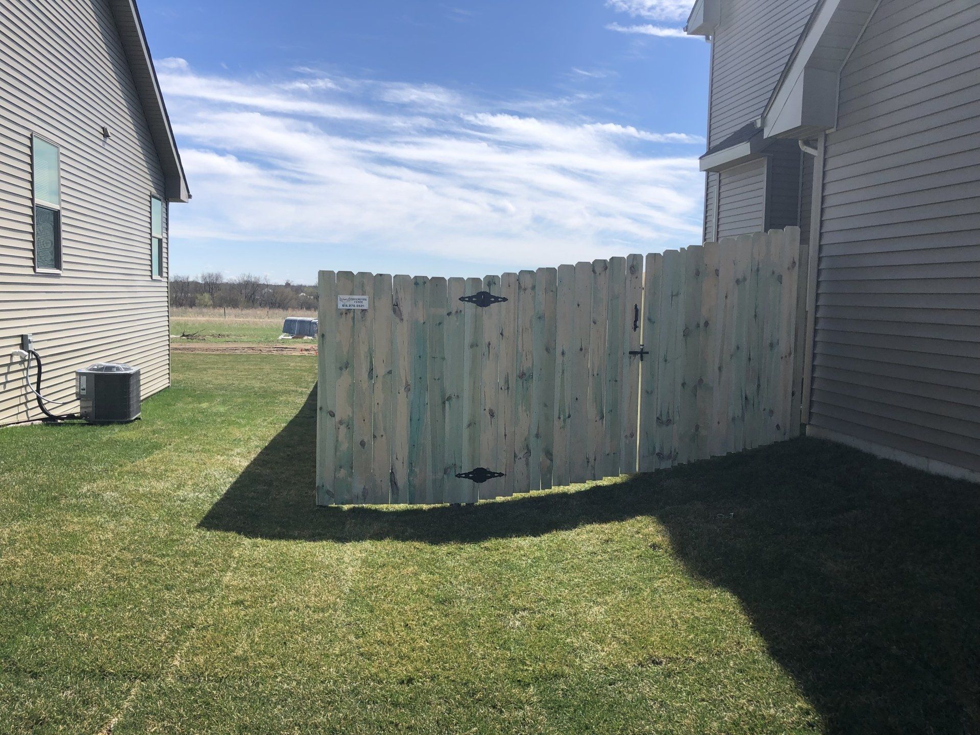 A wooden fence is in the backyard of a house.
