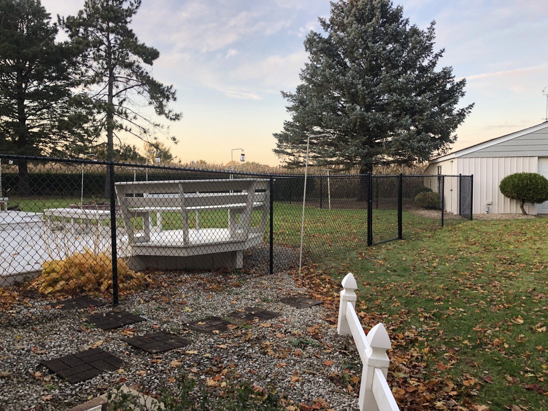 A backyard with a chain link fence and a bench.