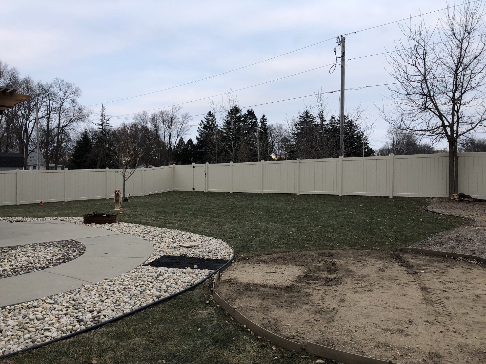 A backyard with a white fence and a fire pit
