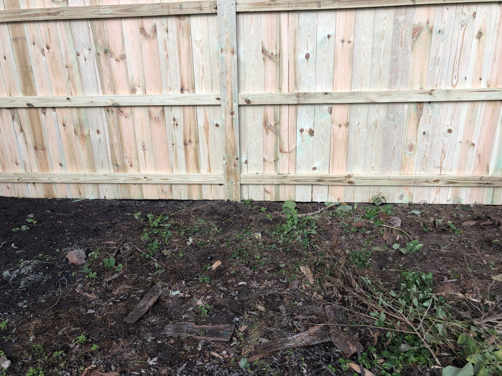 A wooden fence is sitting in the middle of a dirt field.