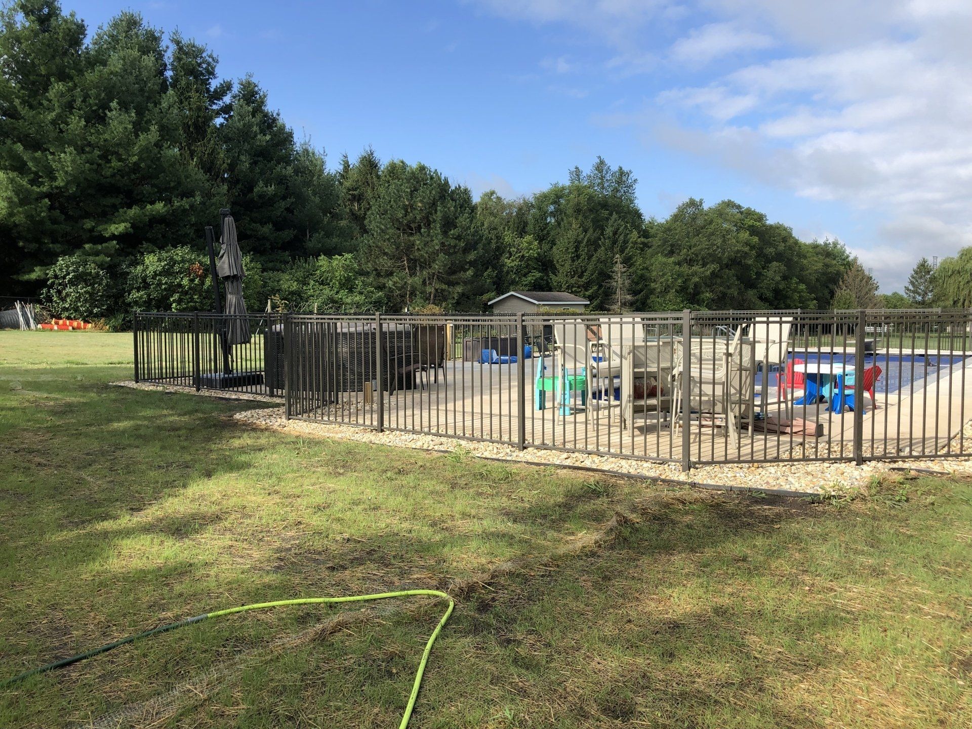 A metal fence surrounds a swimming pool in a backyard.