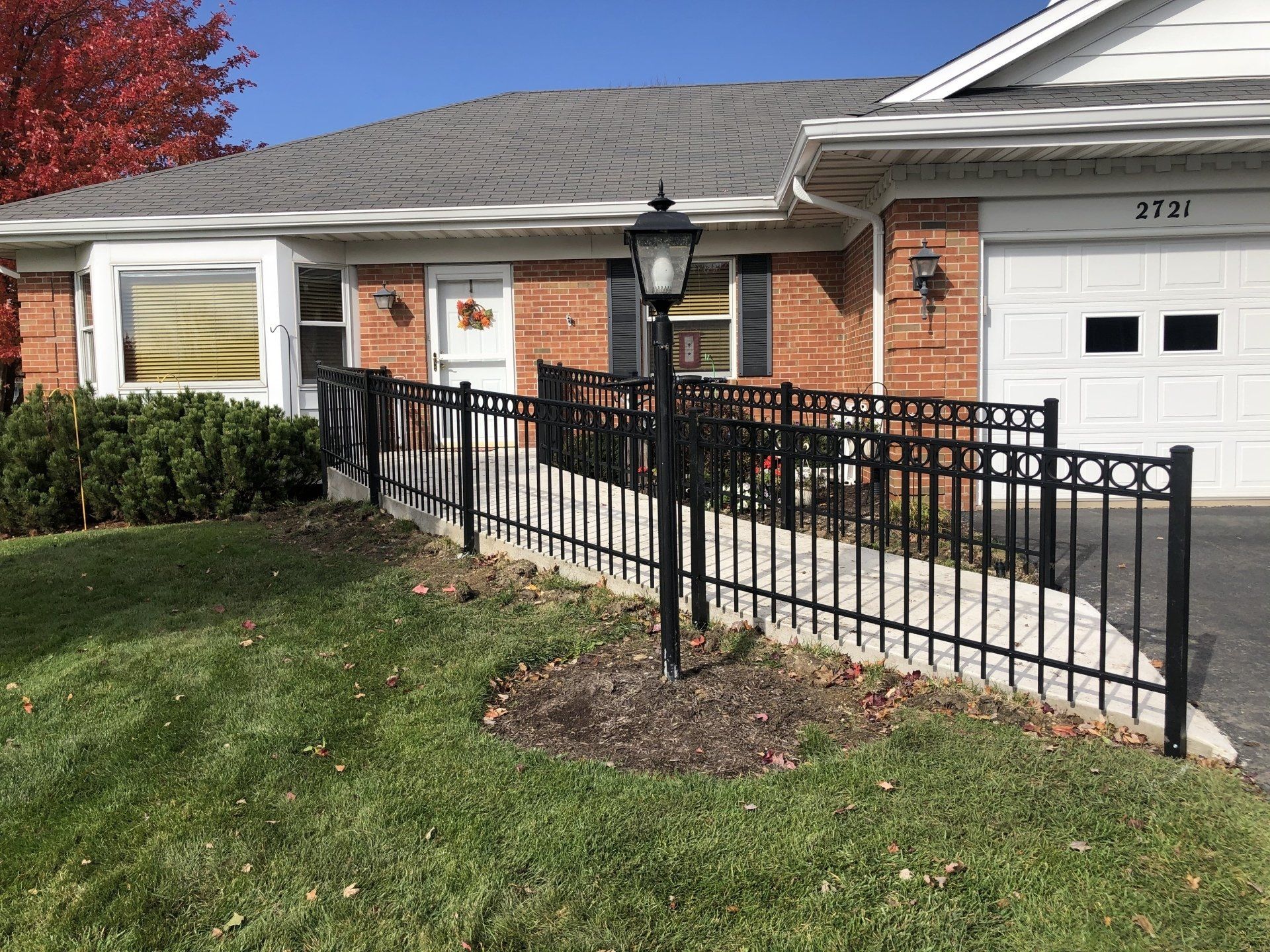 A brick house with a black fence and a ramp in front of it.