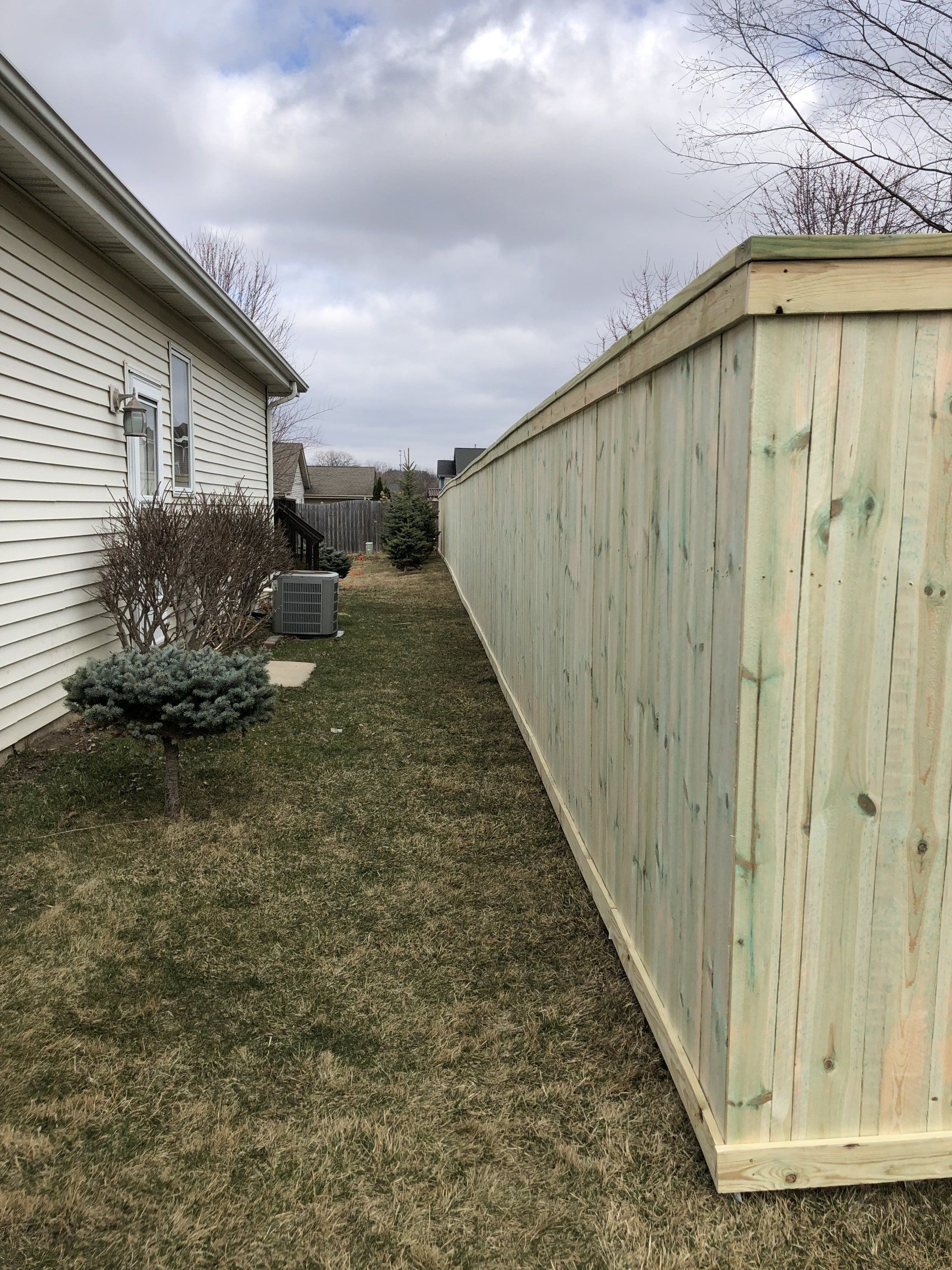 A wooden fence is in the backyard of a house.
