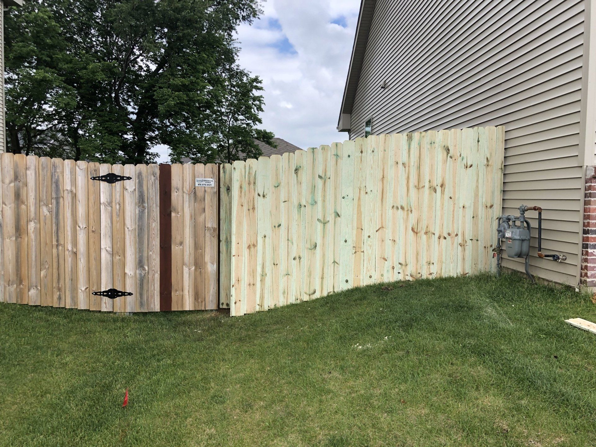 A wooden fence with a gate in the backyard of a house.