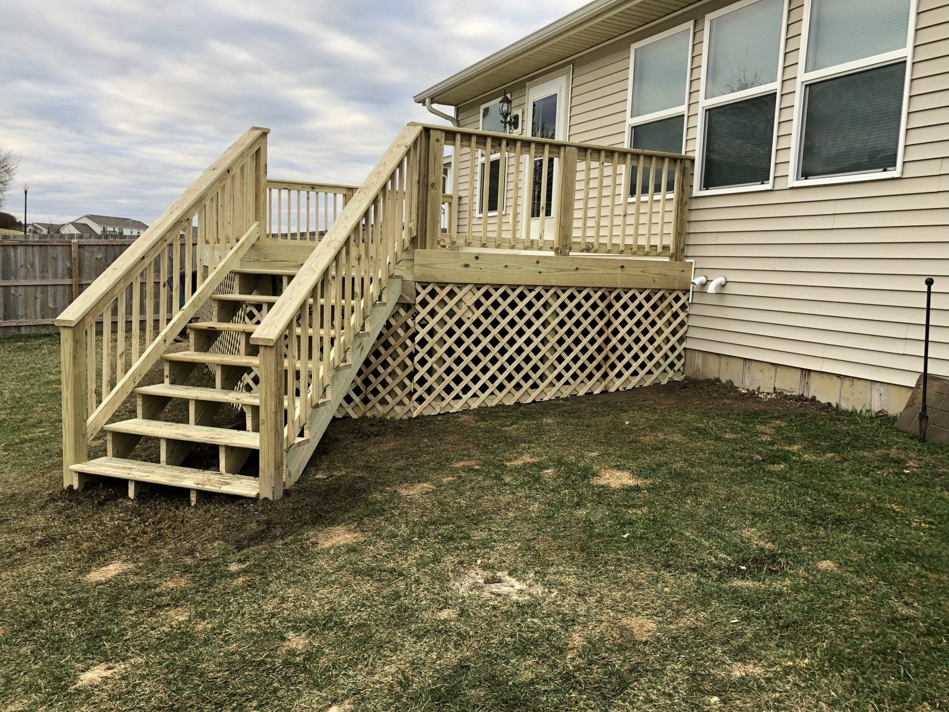 A wooden deck with stairs is in the backyard of a house.