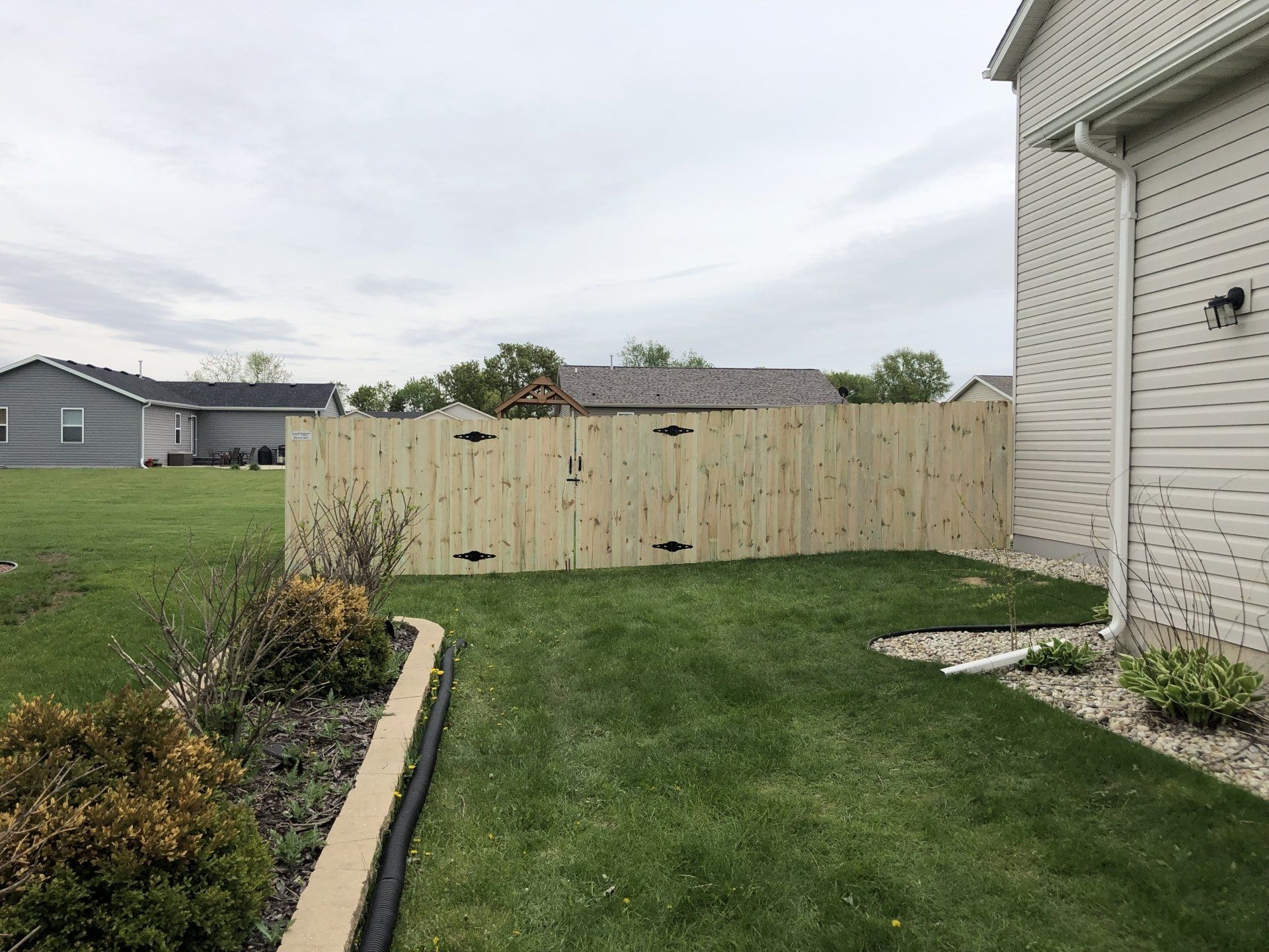 A wooden fence is in the backyard of a house.
