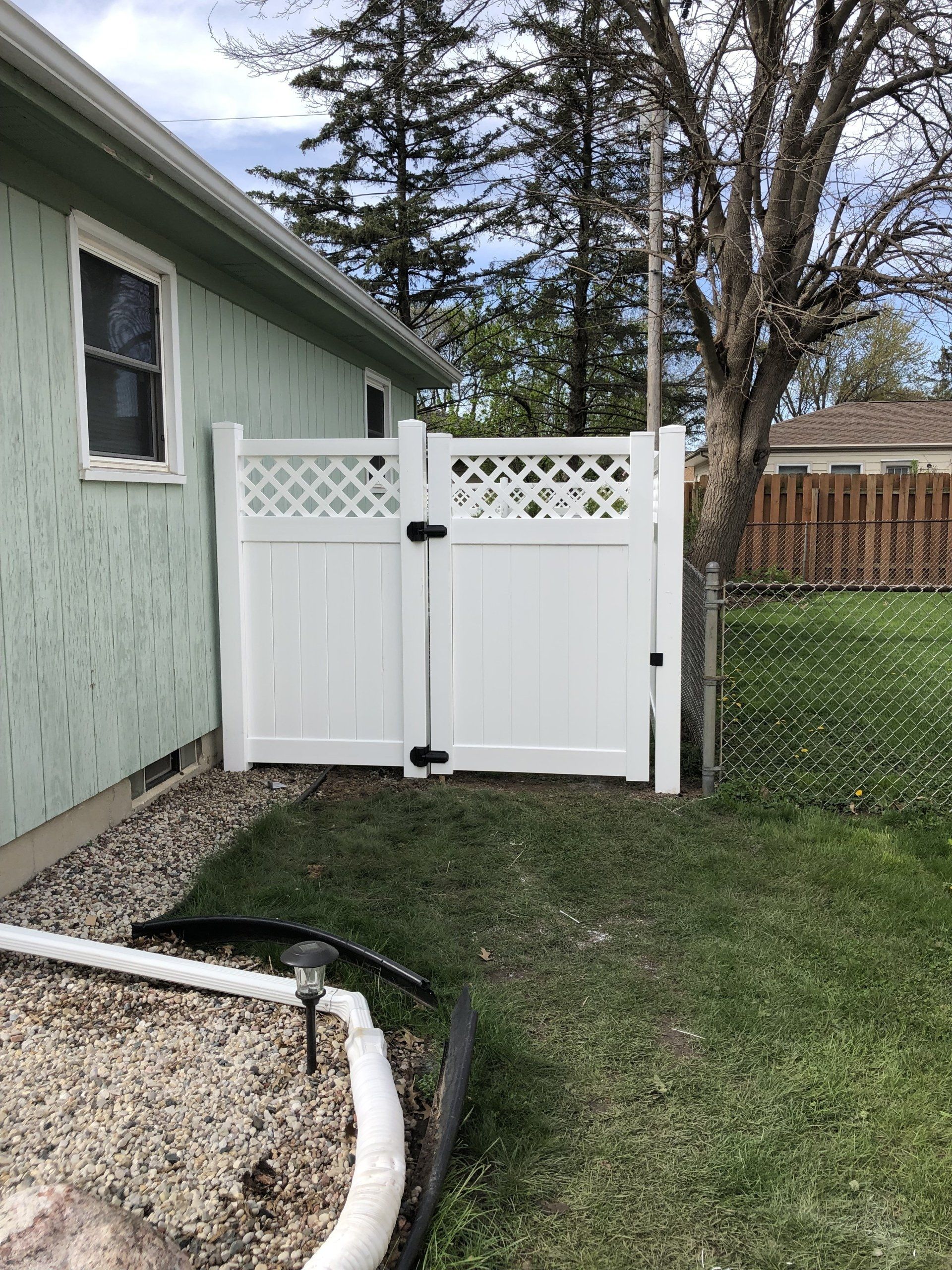 A white fence is in the backyard of a house.