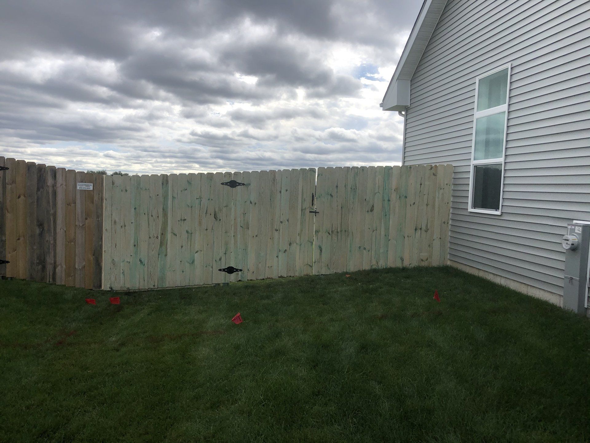 A wooden fence is in the backyard of a house.