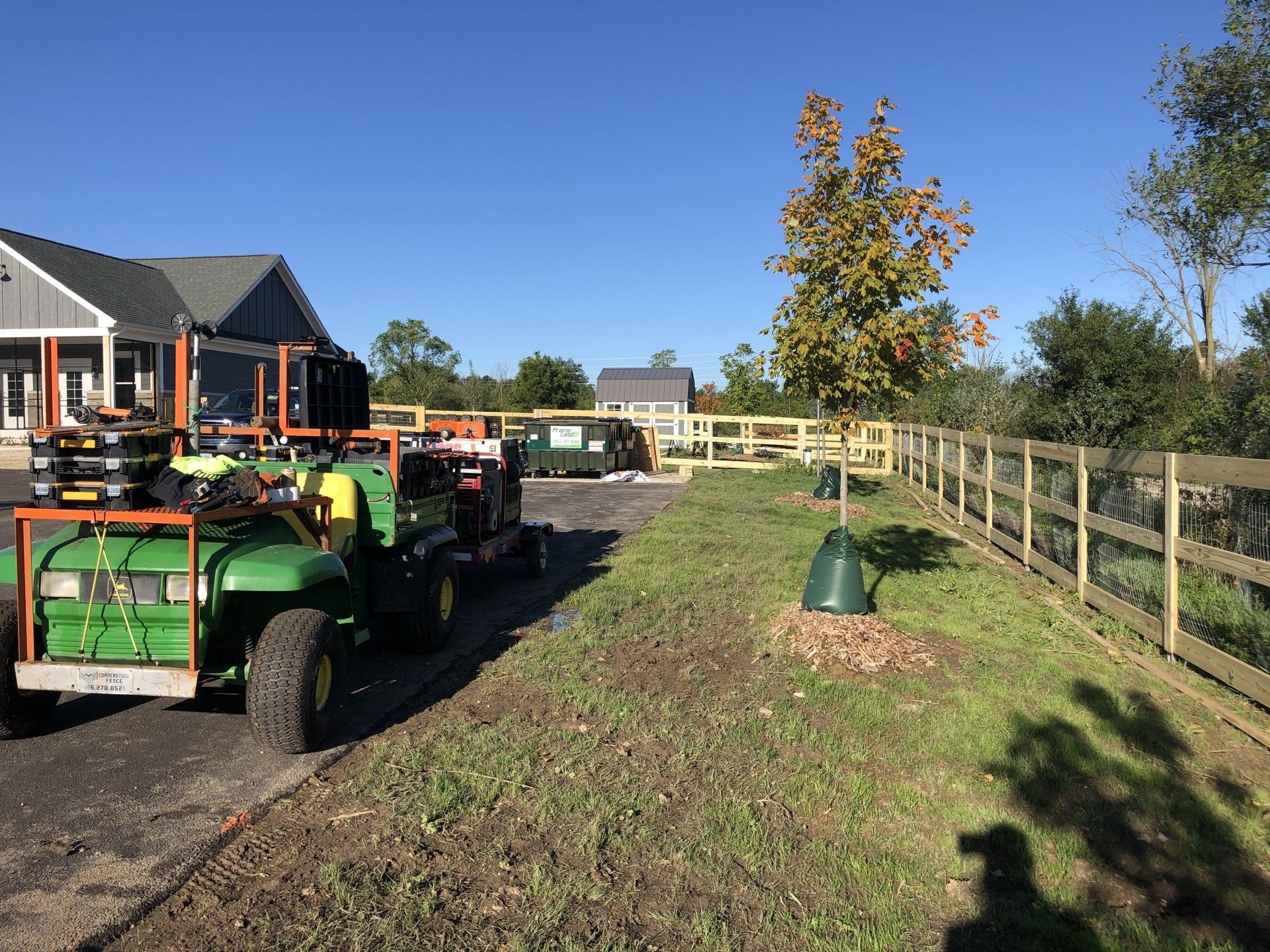 A green tractor is parked on the side of the road in front of a house.