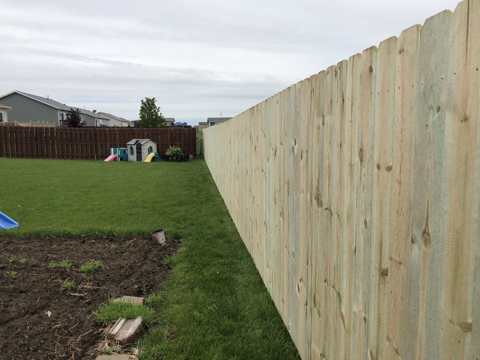 A wooden fence is surrounding a lush green yard.