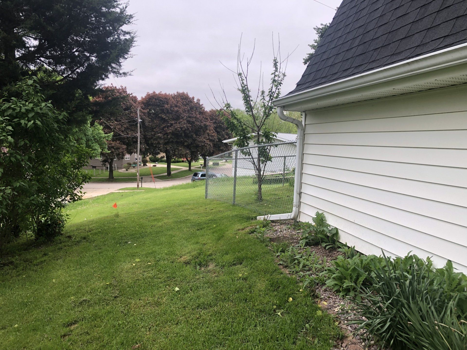 A white house with a black roof is sitting on top of a lush green field.