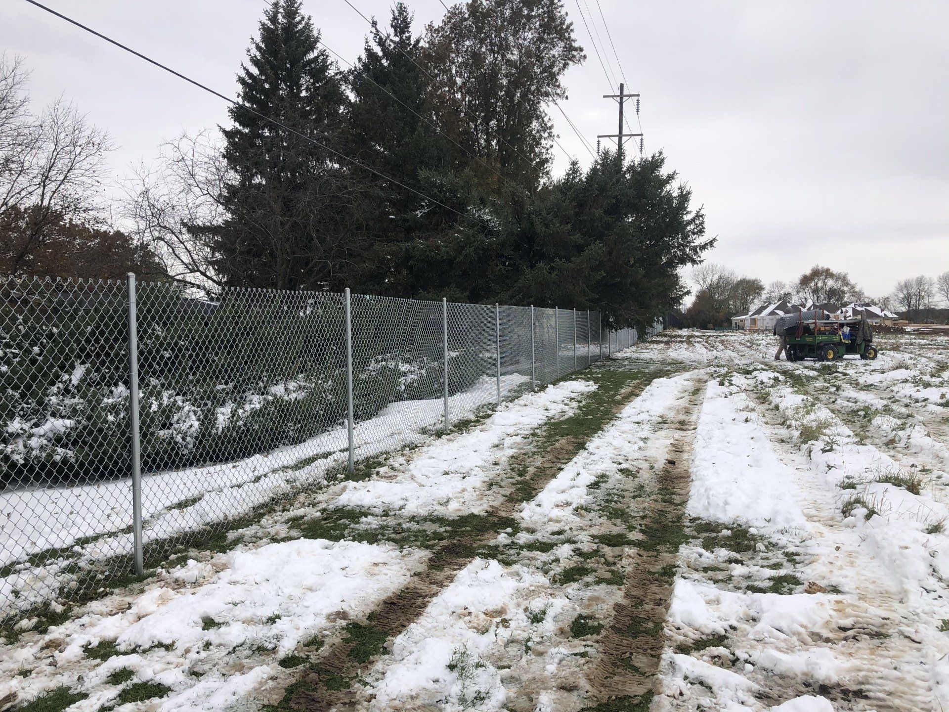 A snowy road with a chain link fence in the background
