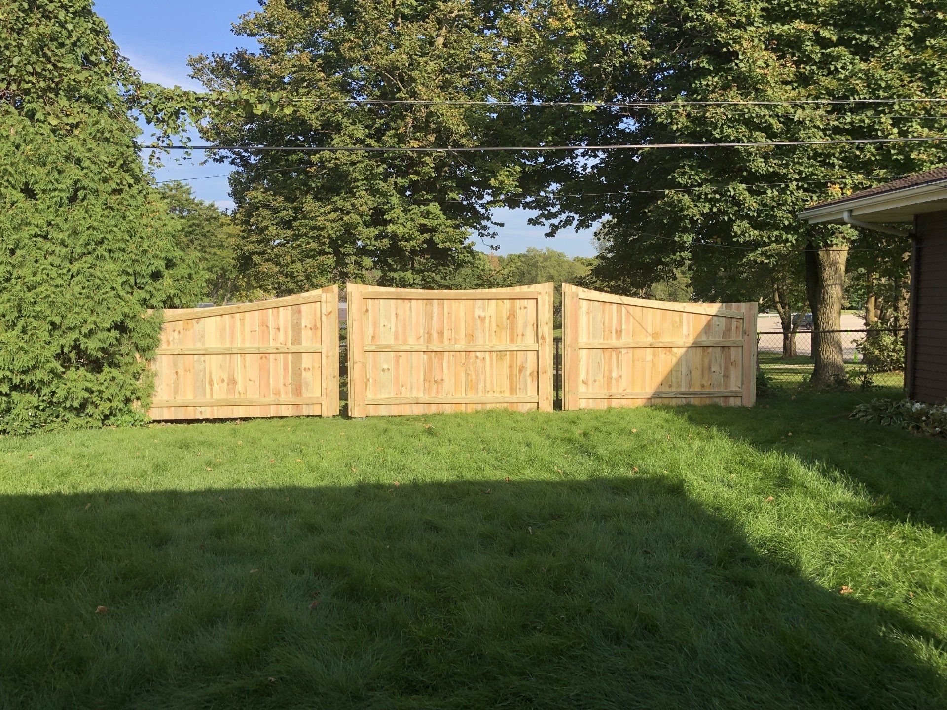 A wooden fence is in the middle of a lush green field.