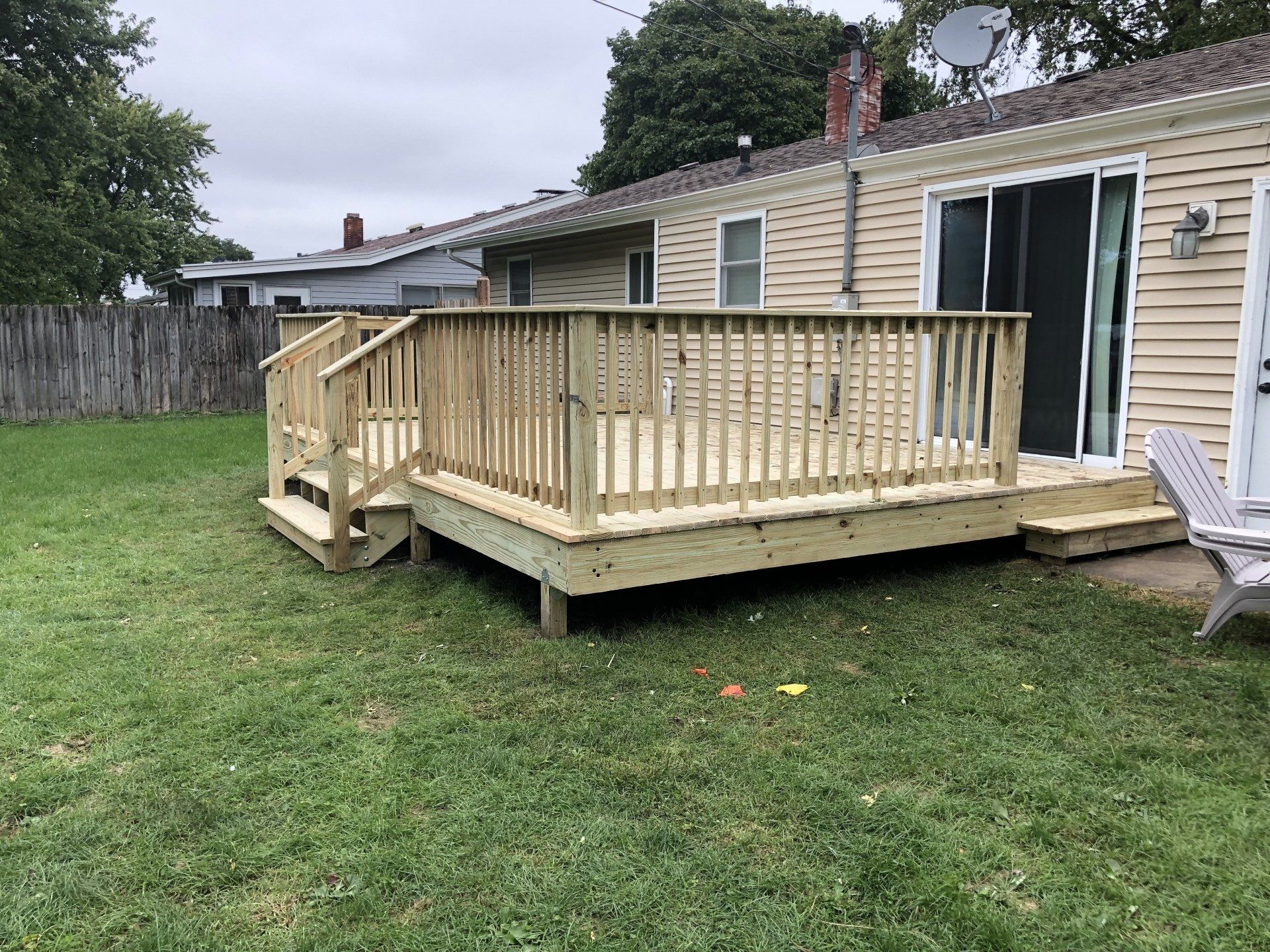 A wooden deck with stairs is in the backyard of a house.