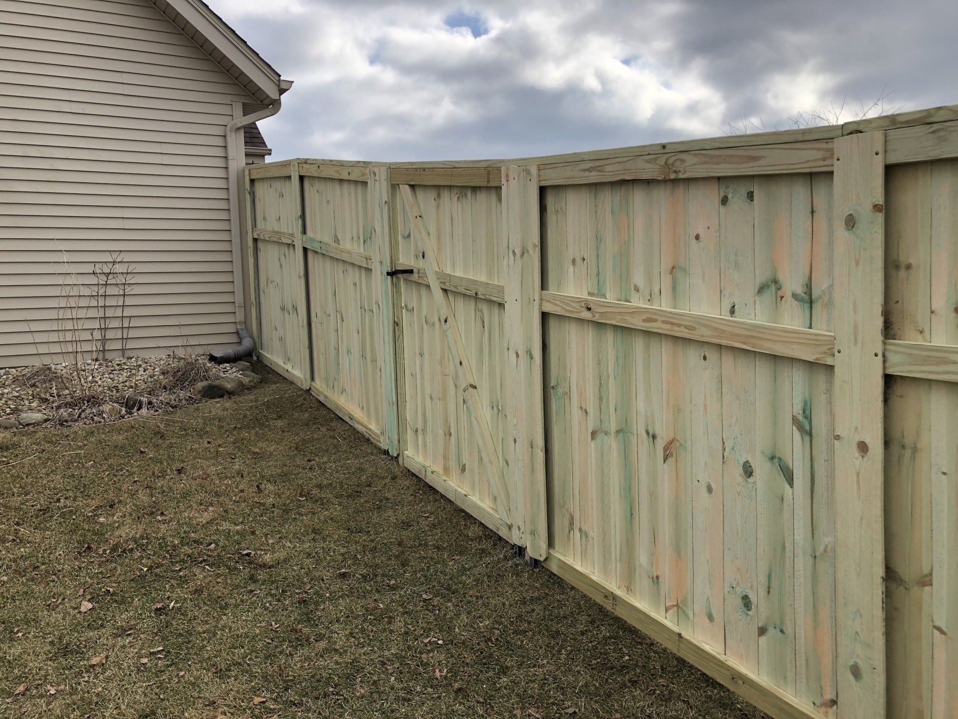 A wooden fence with a gate in the backyard of a house.
