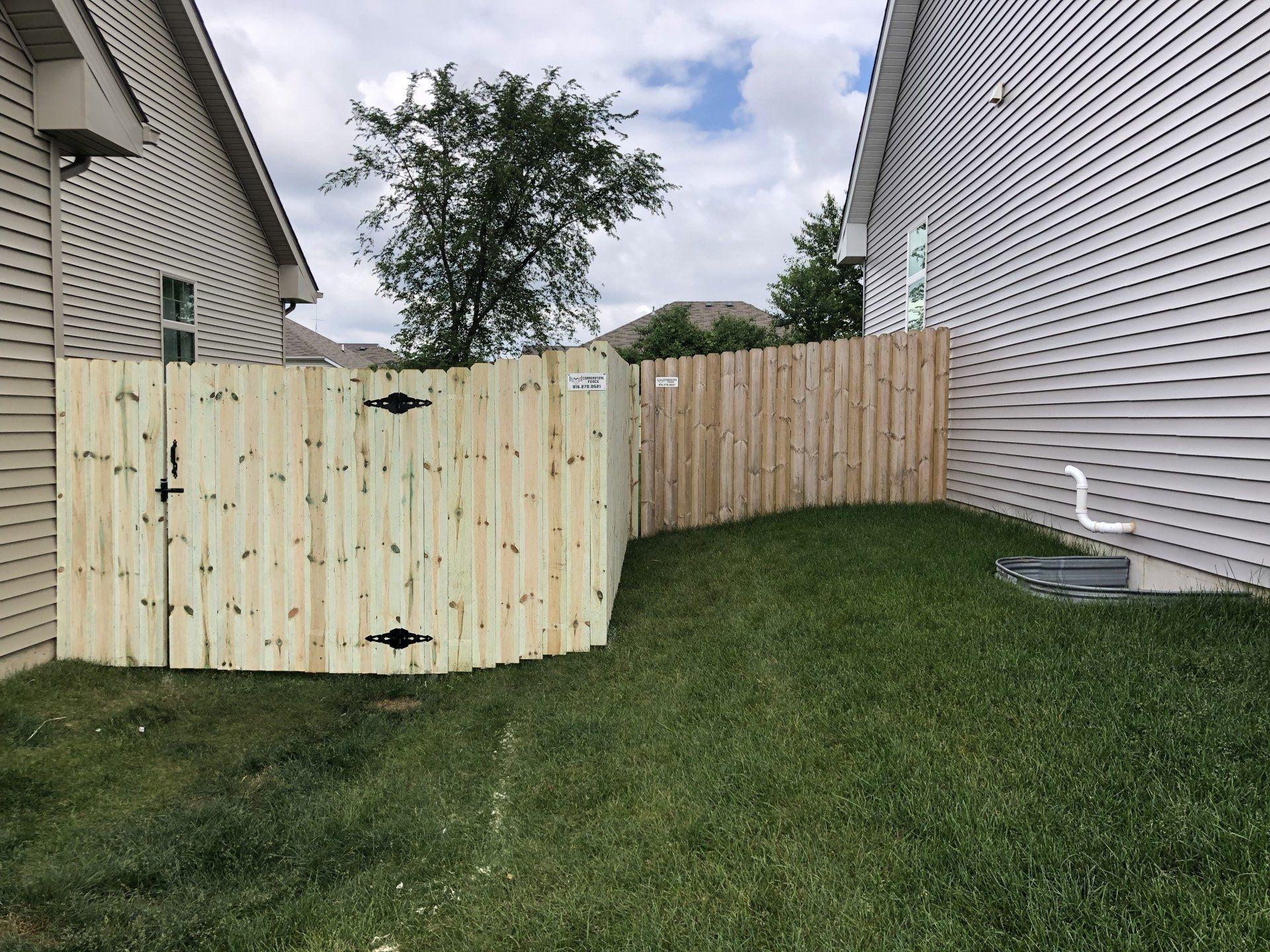 A wooden fence is in the backyard of a house.