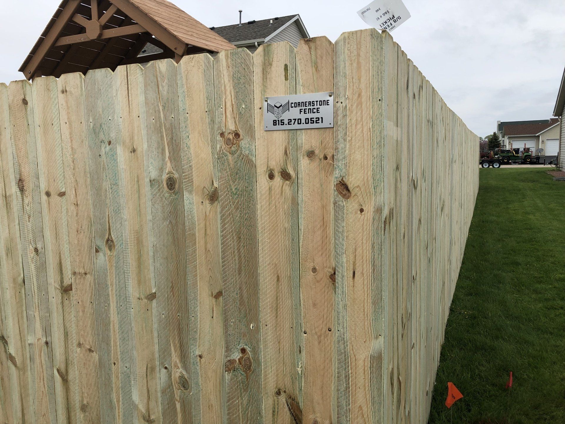 A wooden fence with a sign on it in front of a house.