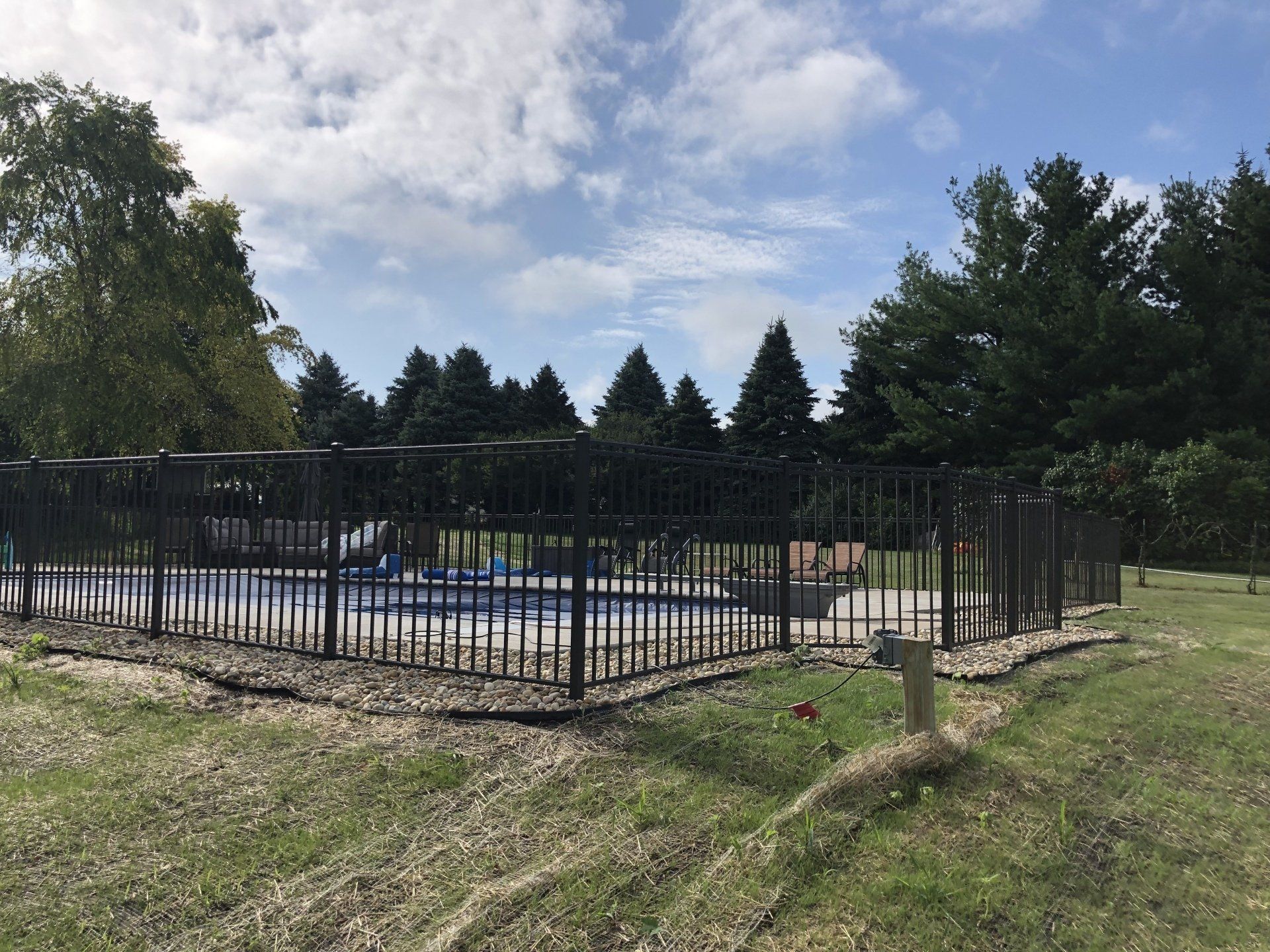 A fence around a swimming pool with trees in the background