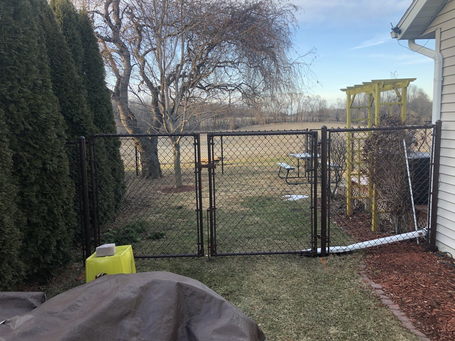 A chain link fence is in the backyard of a house.
