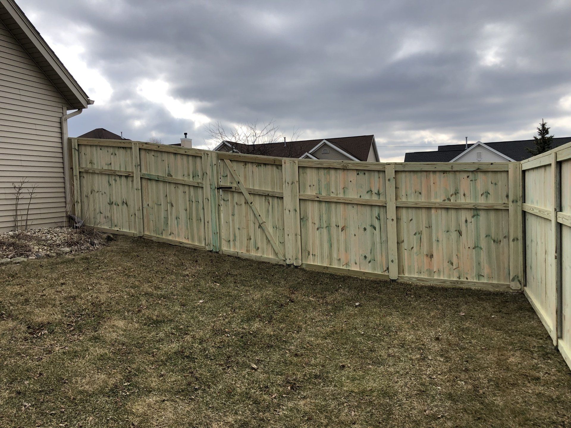 A wooden fence is in the backyard of a house.
