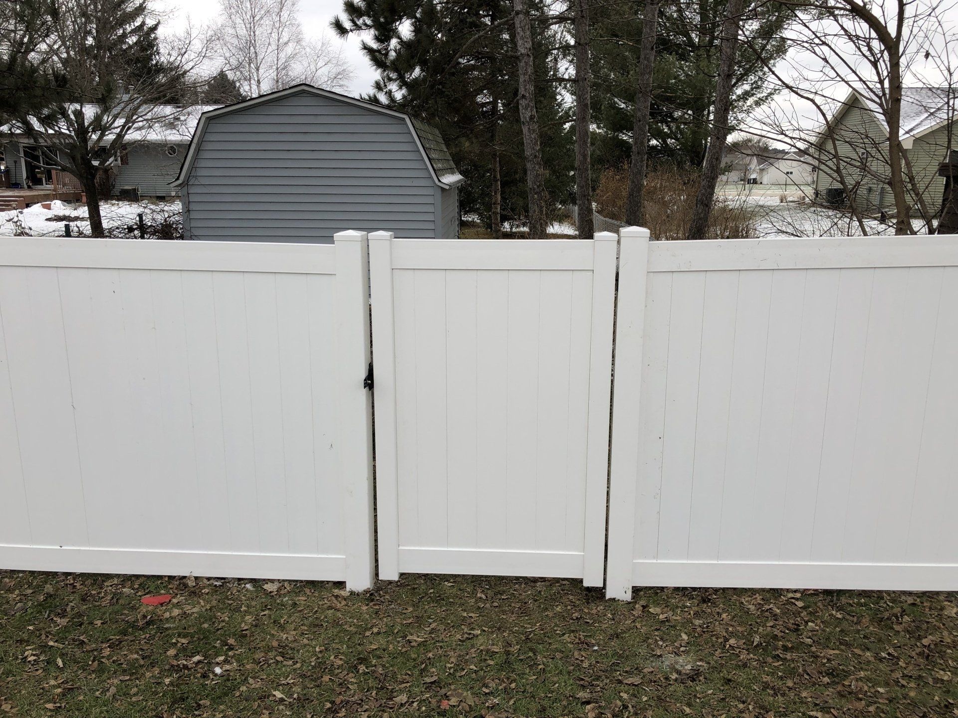 A white fence with a gate and a barn in the background.