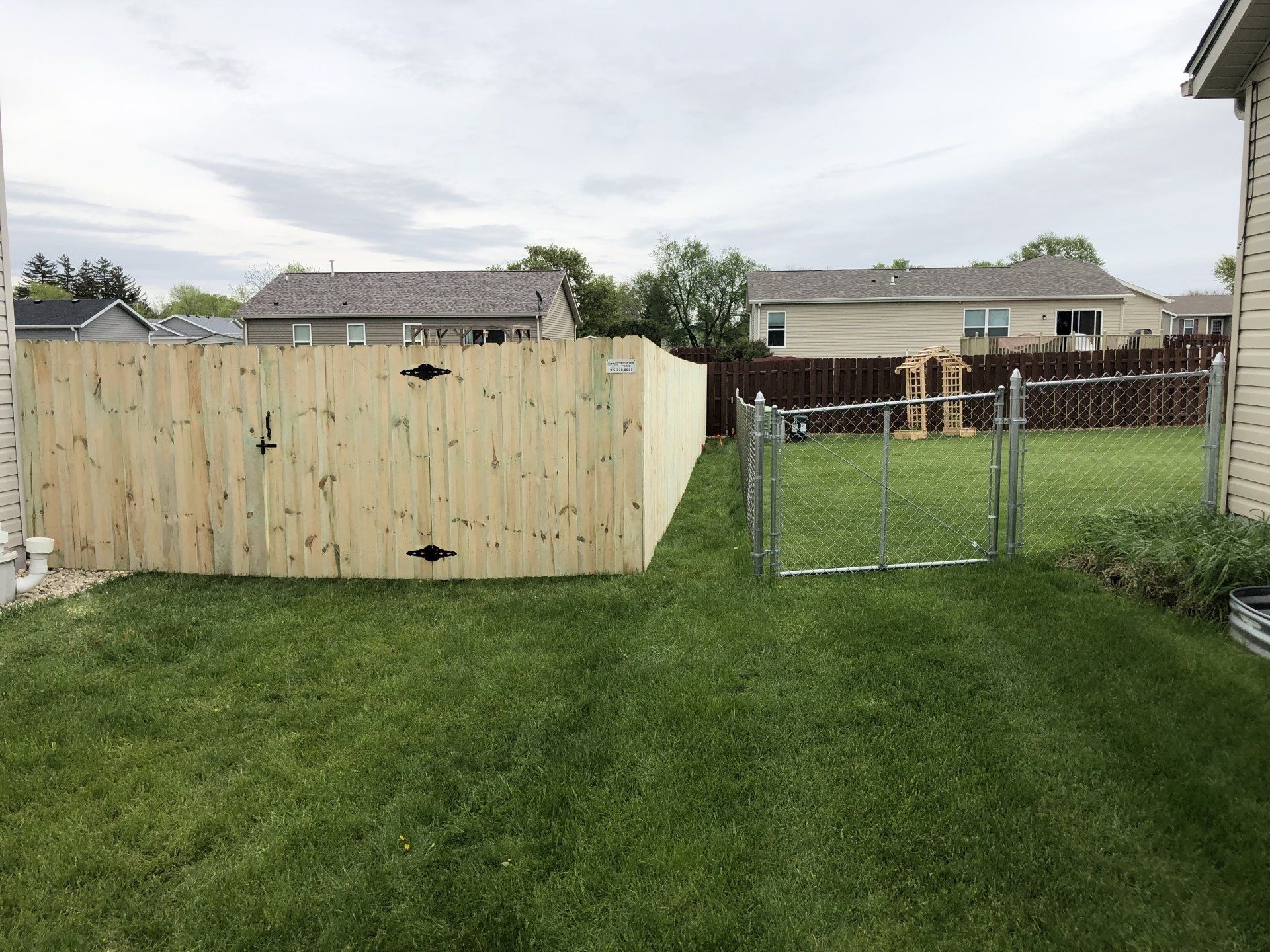 A backyard with a wooden fence and a chain link fence.