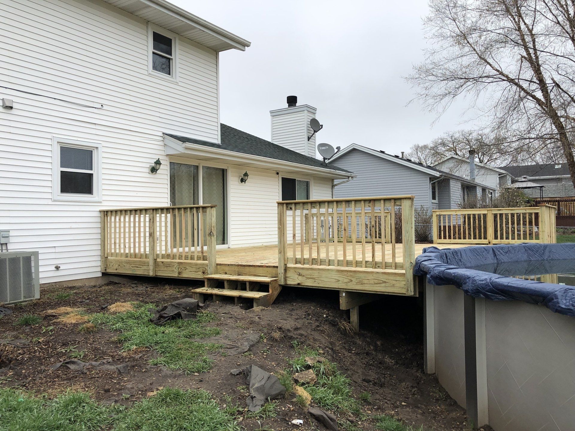 A wooden deck is being built in the backyard of a house next to a pool.