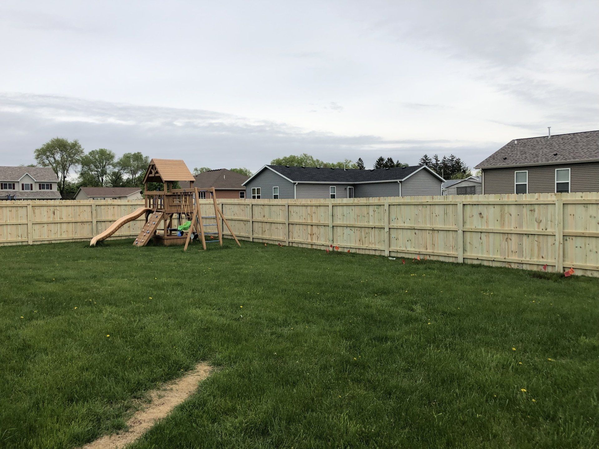 A backyard with a wooden fence and a swing set.