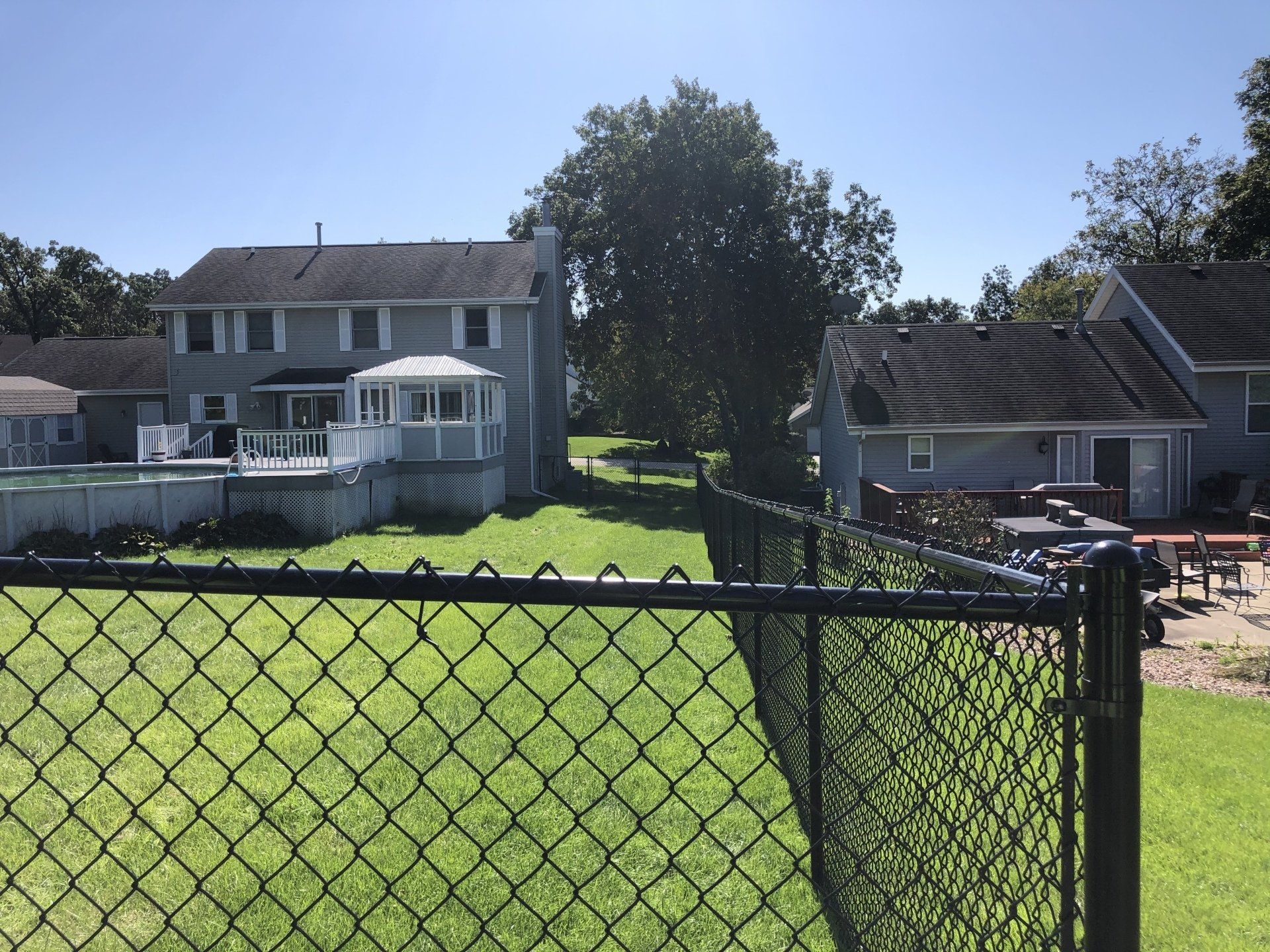 A chain link fence surrounds a lush green yard
