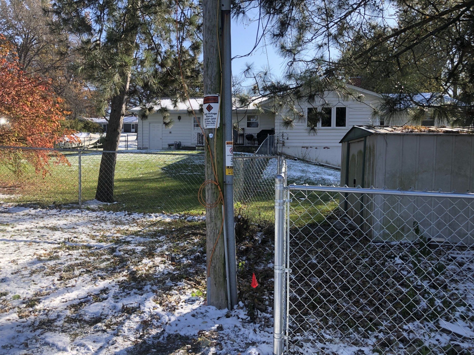 A chain link fence is surrounding a yard with a house in the background.