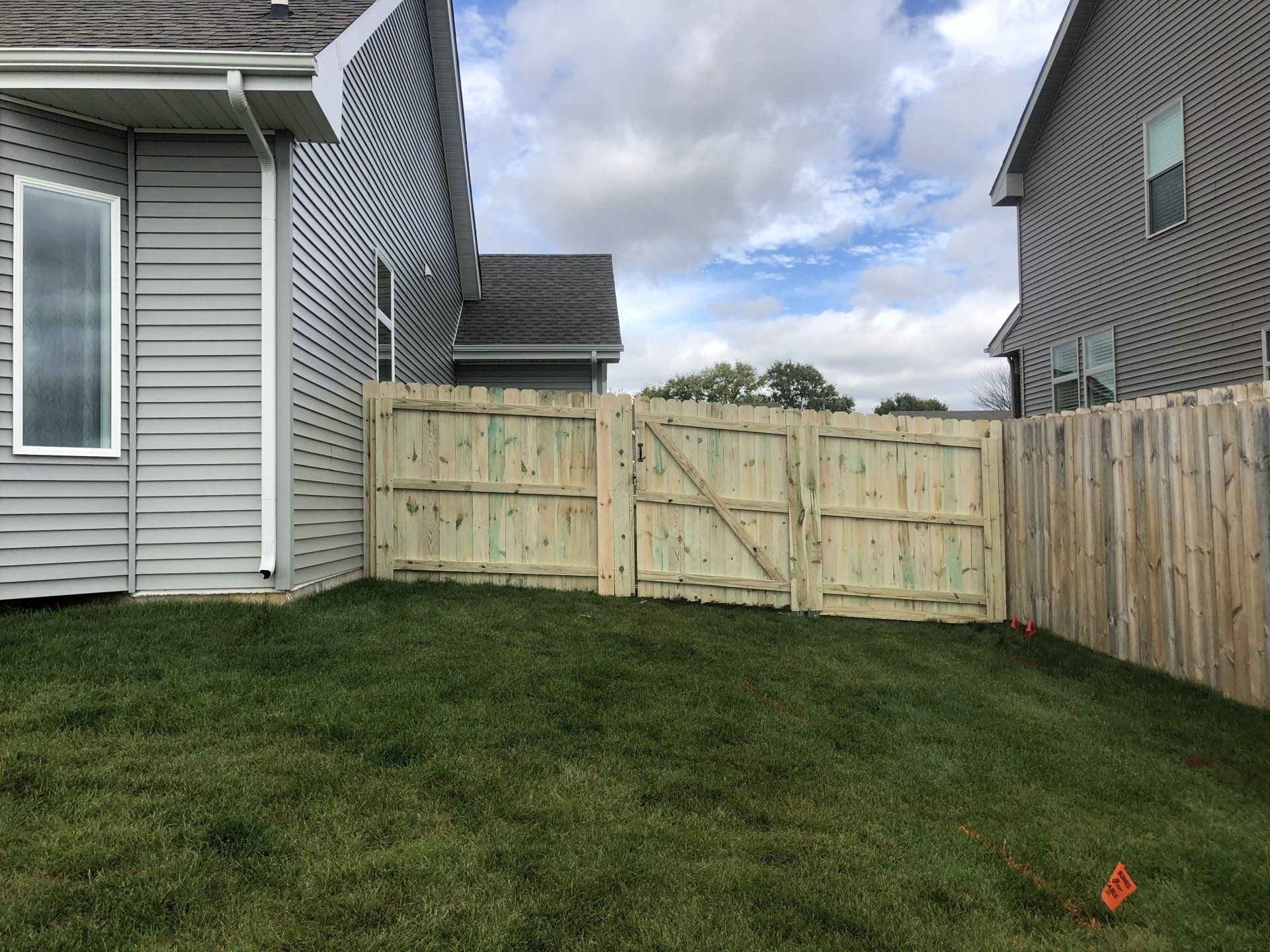 A wooden fence is in the backyard of a house.