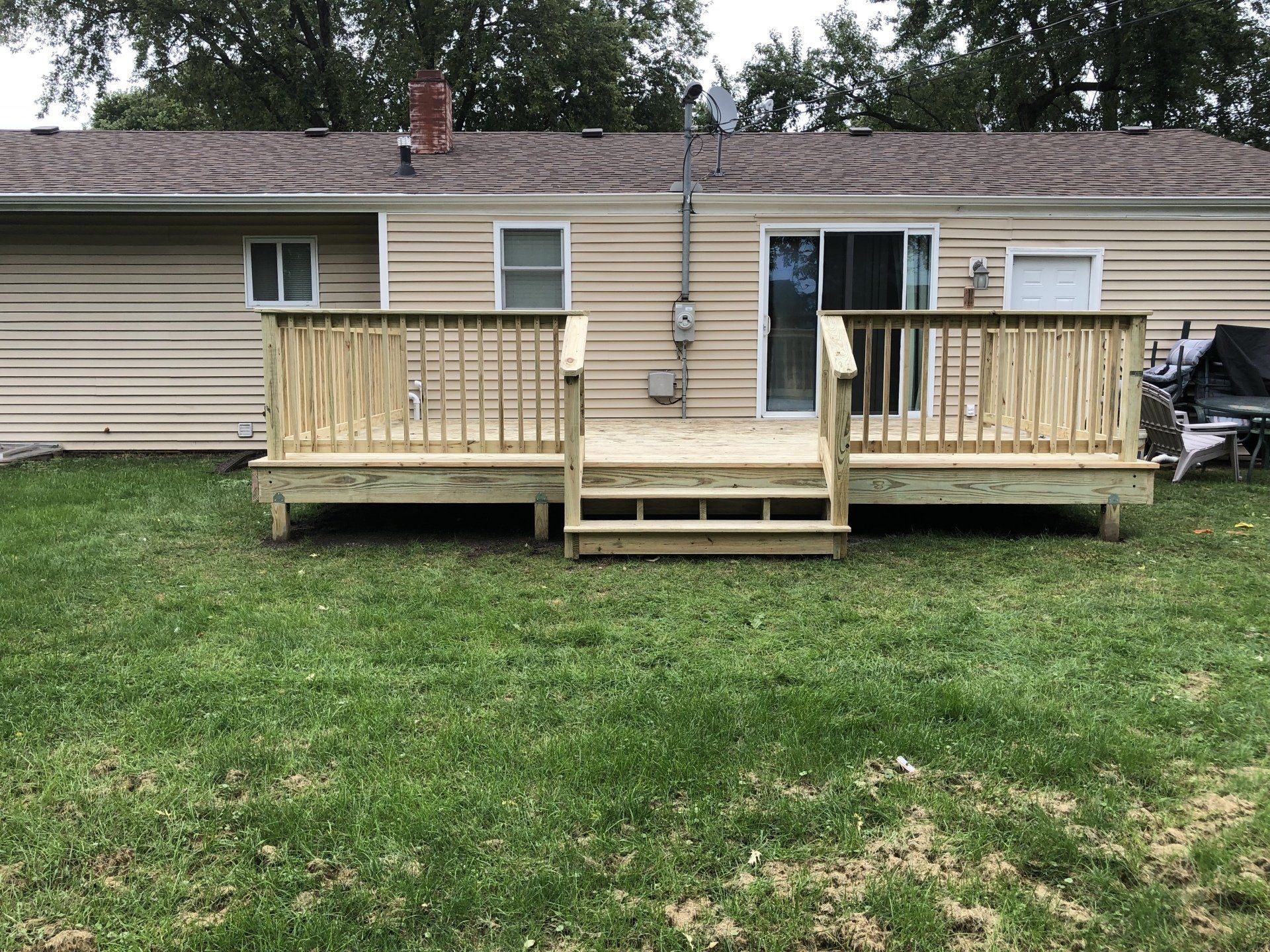 A large wooden deck is in the backyard of a house.