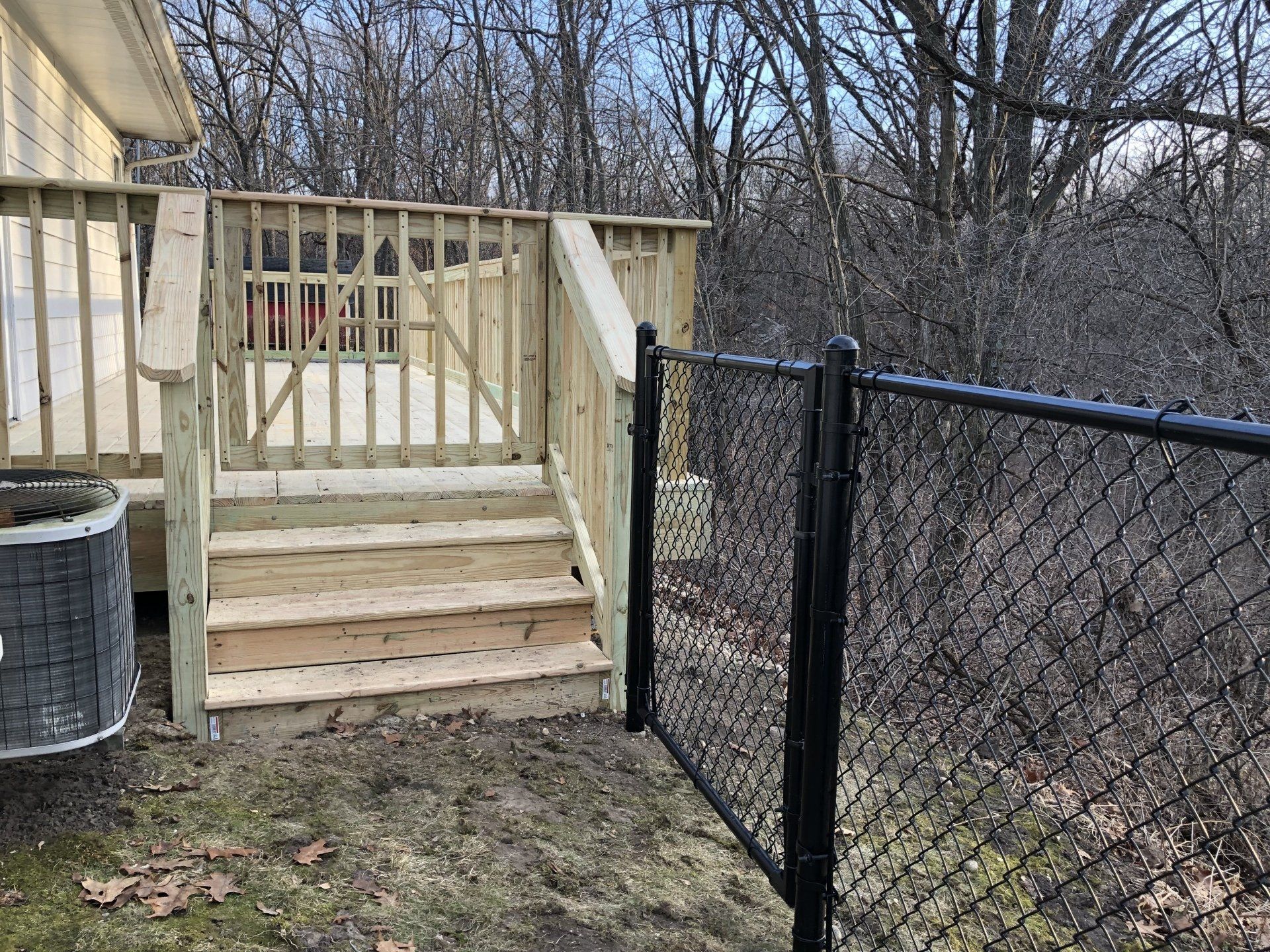 A wooden deck with stairs and a chain link fence surrounding it.