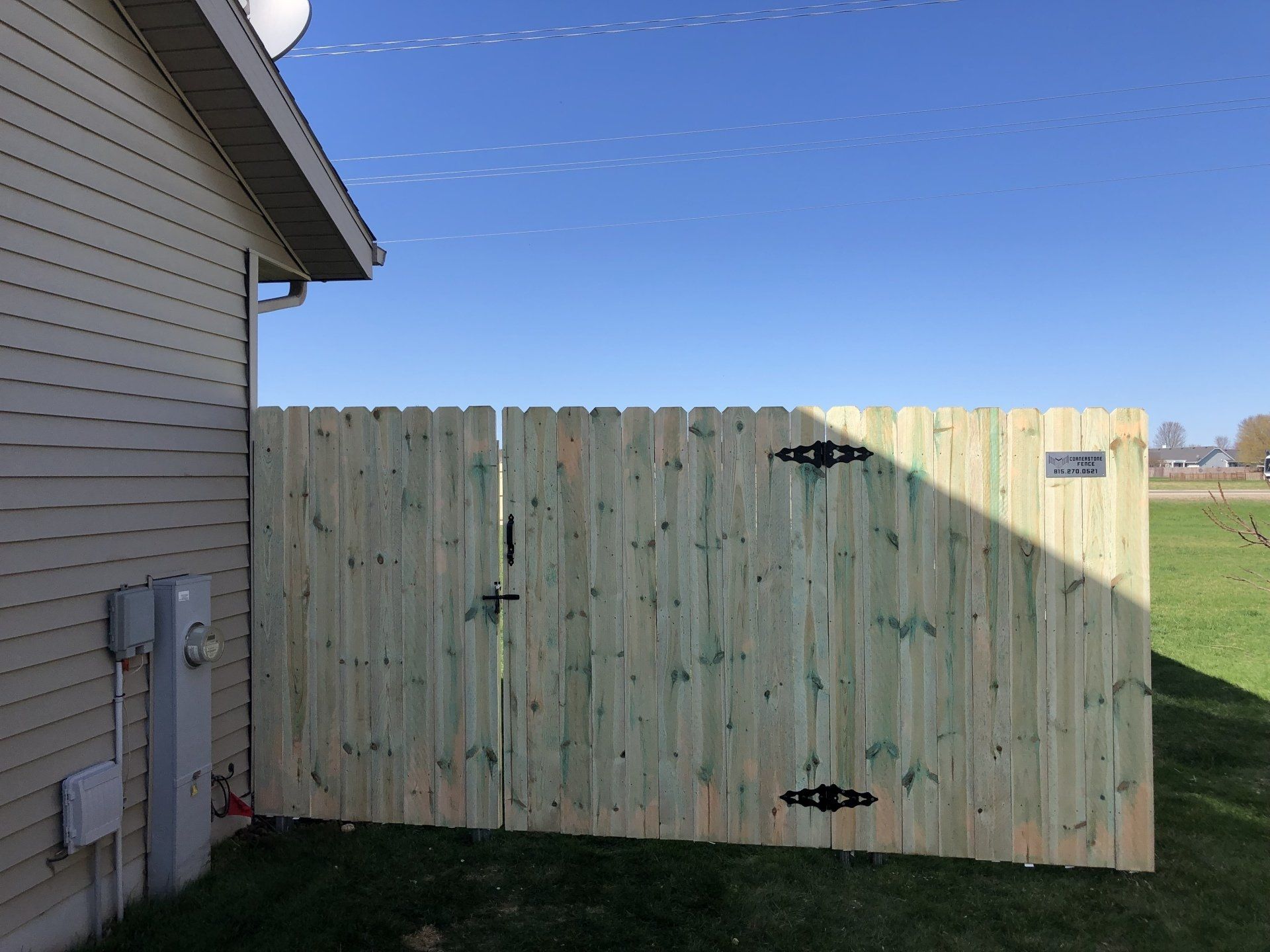 A wooden fence with a gate is next to a house.