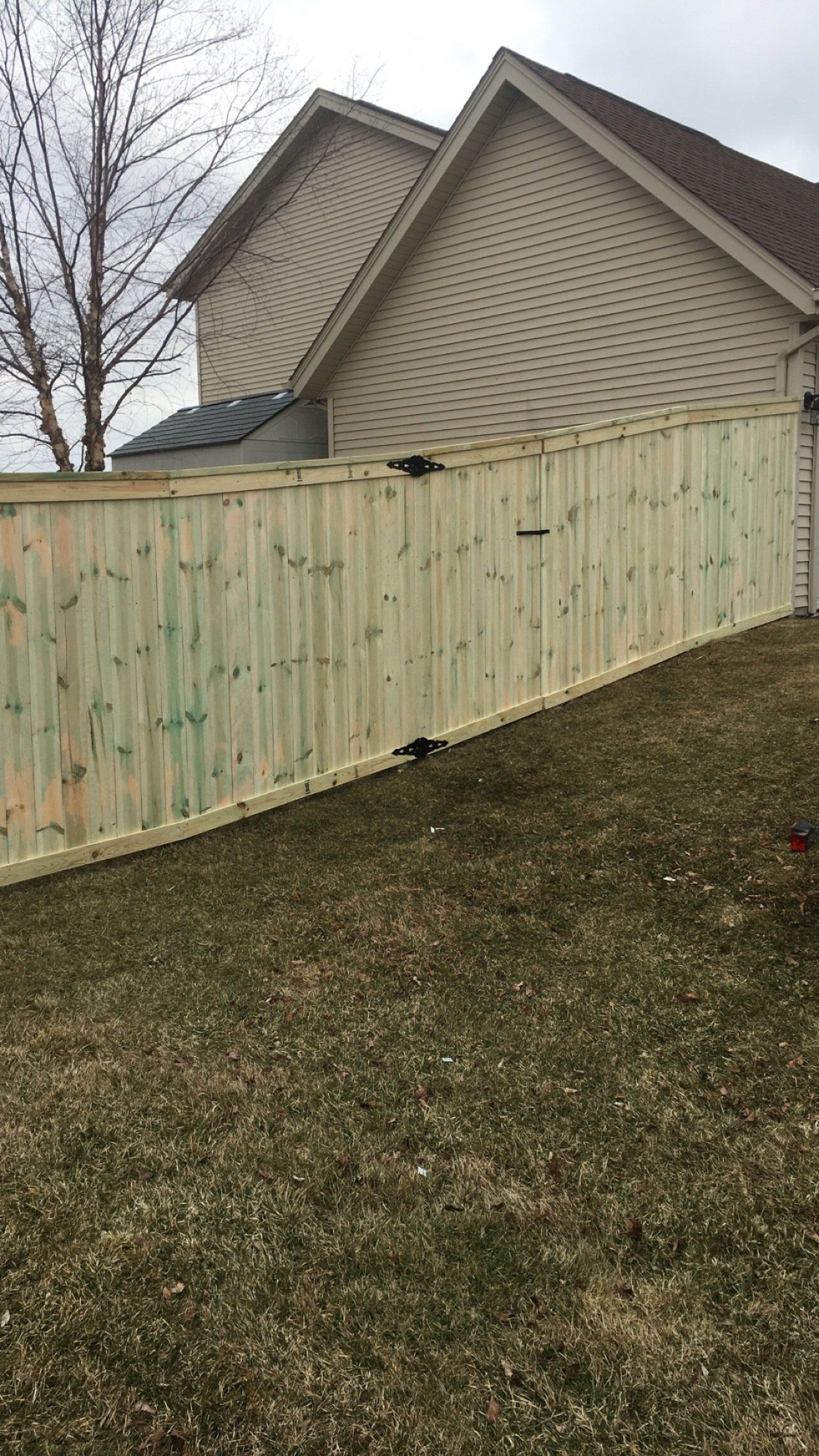 A wooden fence is in the backyard of a house.