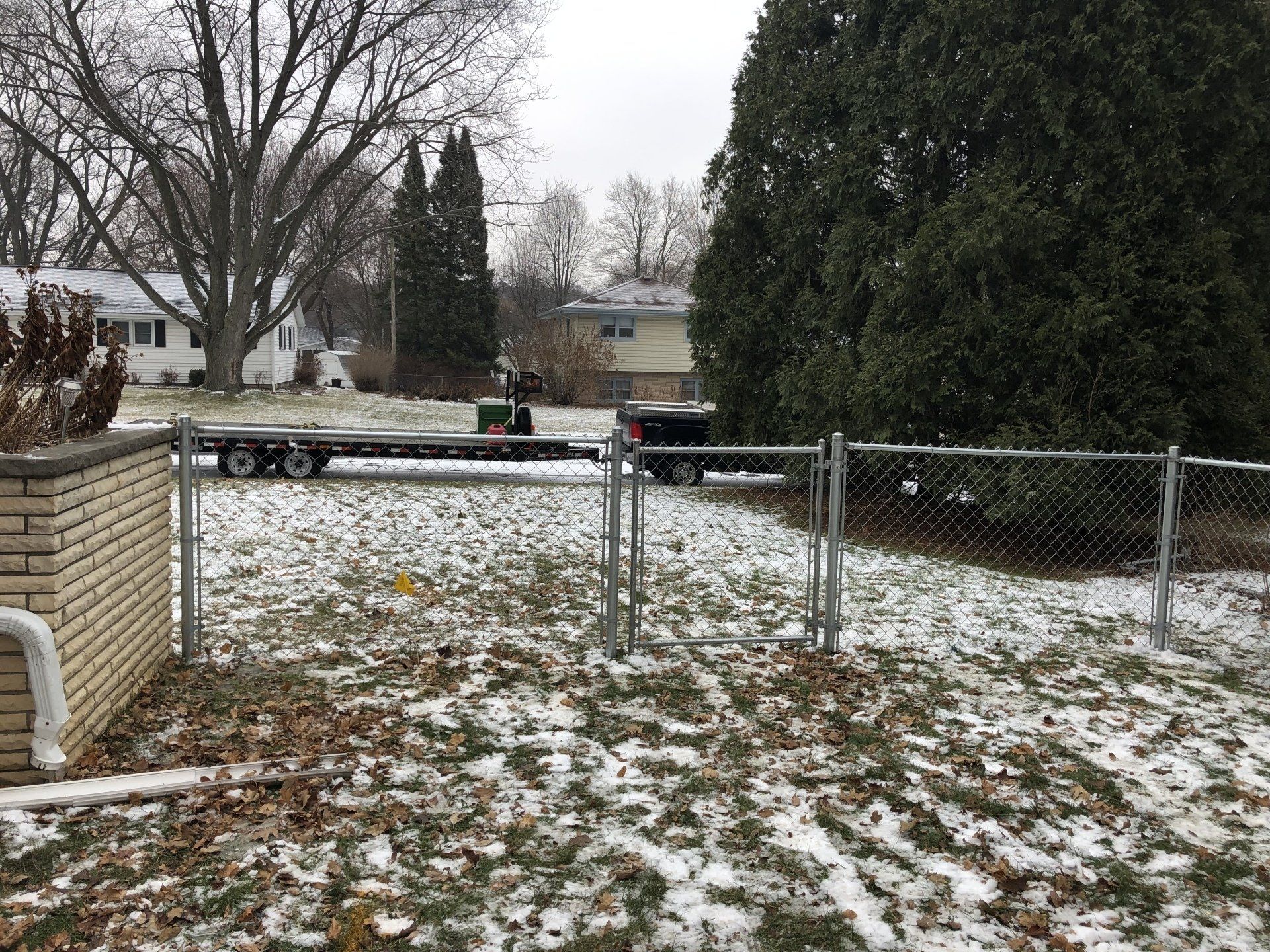 A chain link fence is surrounding a snowy yard.
