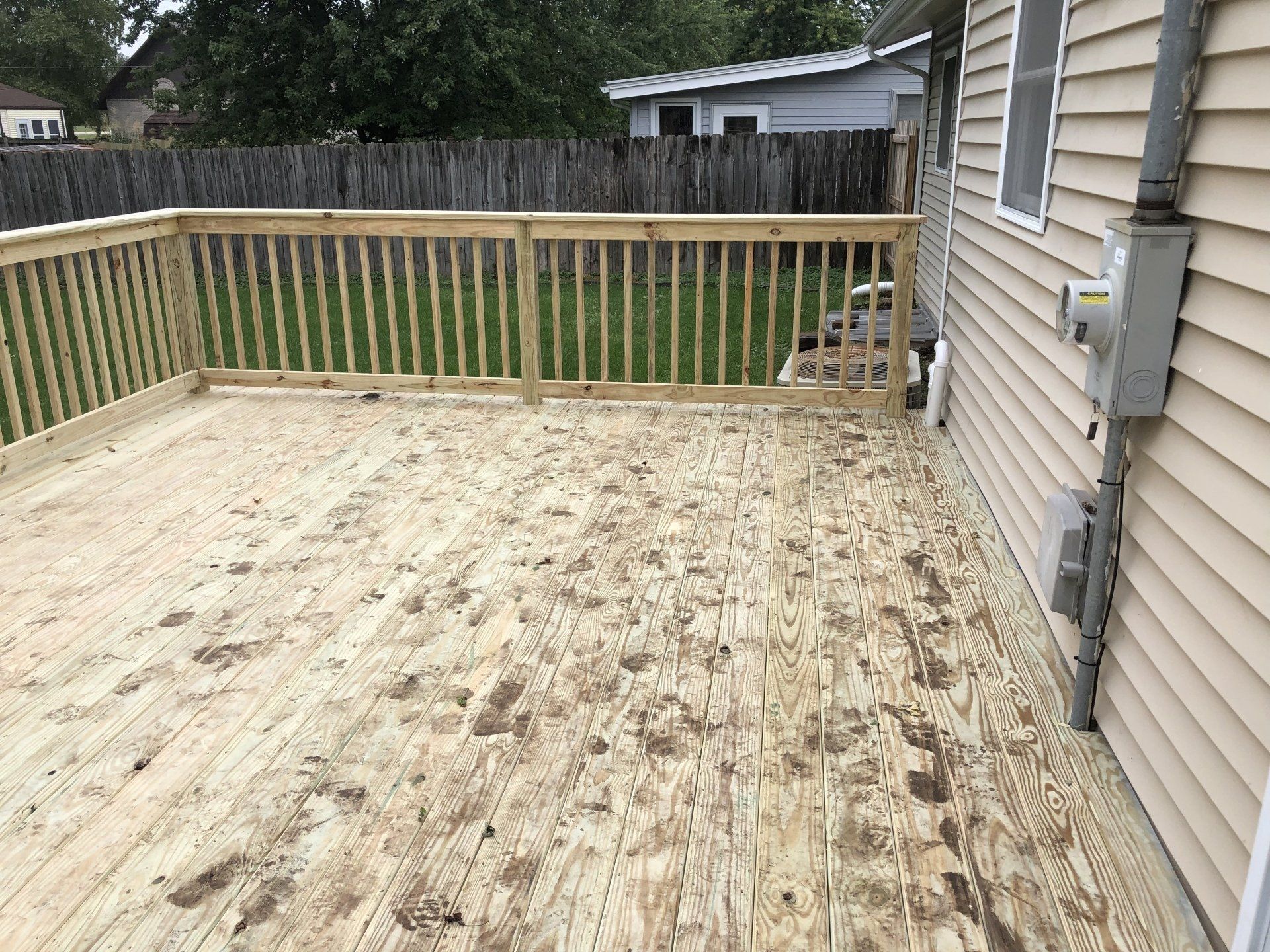A wooden deck with a railing is in front of a house.
