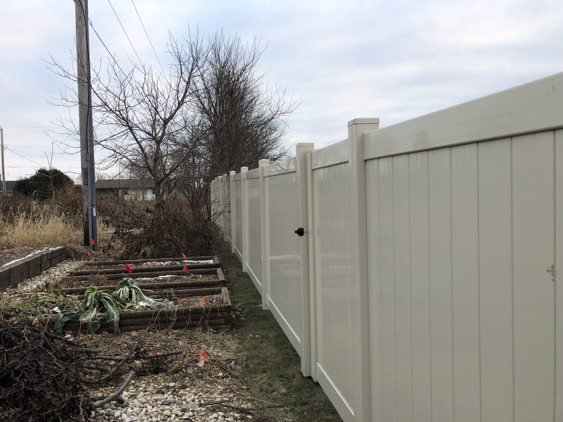 A white fence surrounds a garden with a gate.