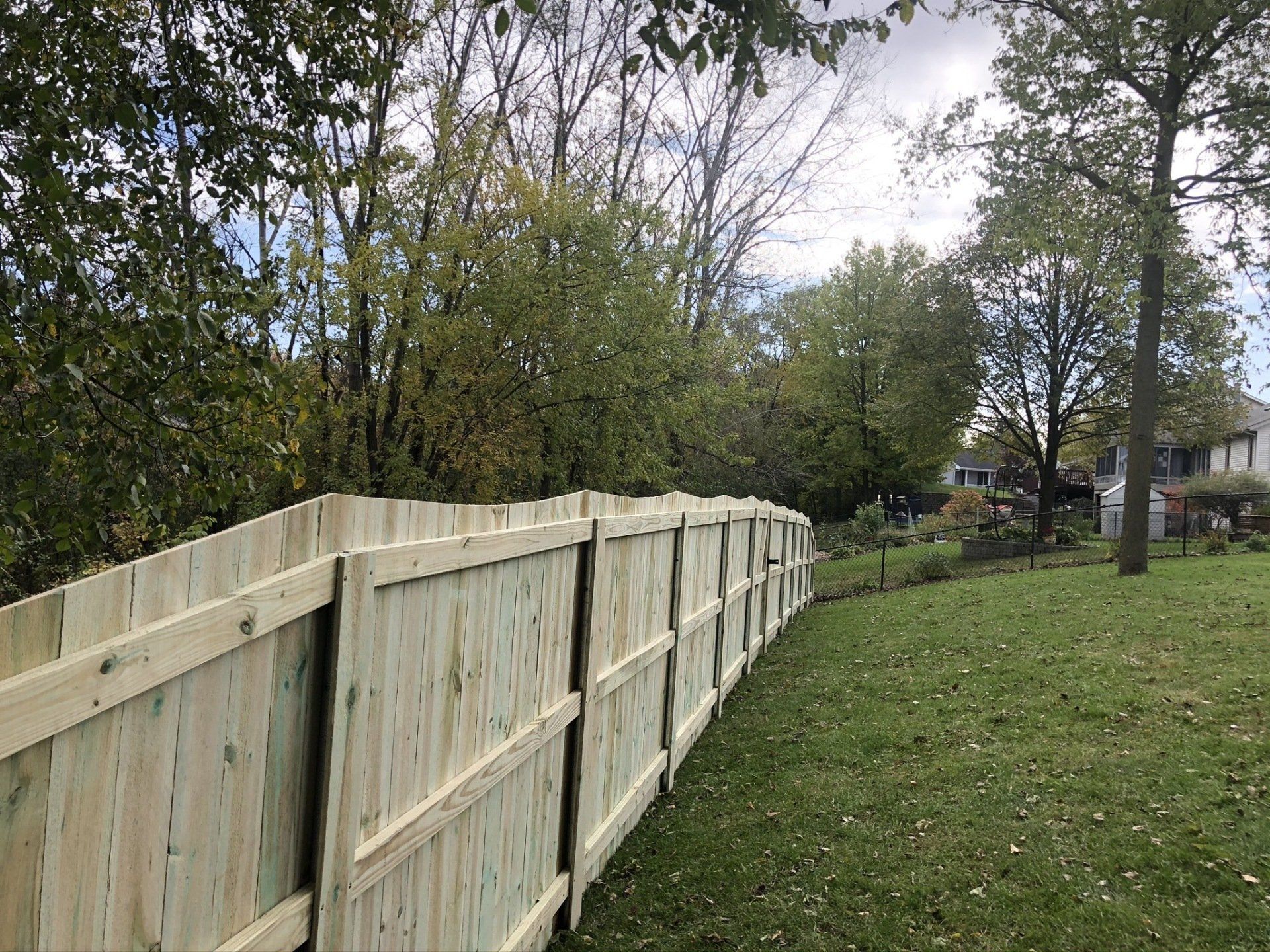 A wooden fence is sitting in the middle of a lush green field.