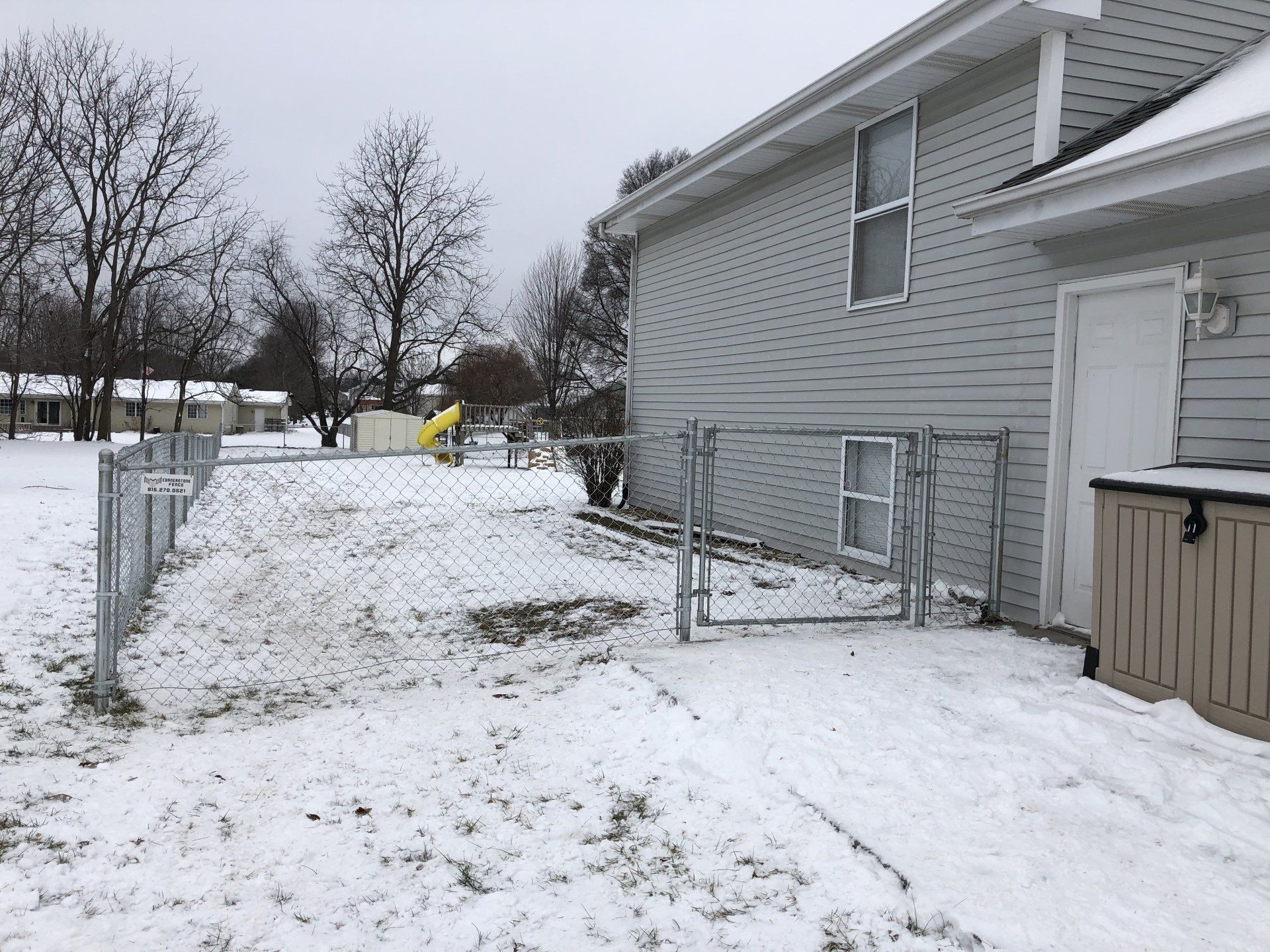 A snowy yard with a house in the background