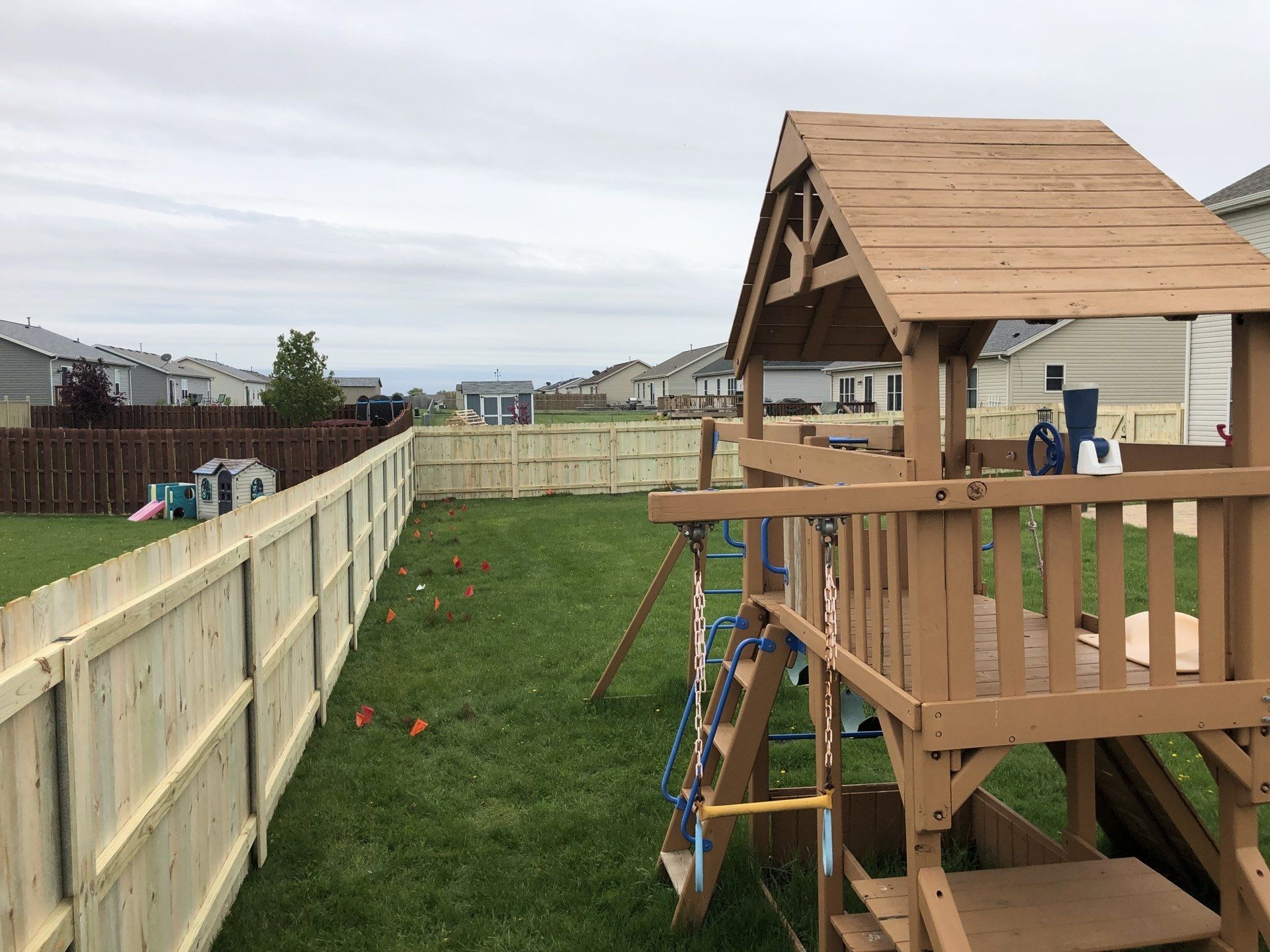 A wooden playground set in a backyard next to a wooden fence.
