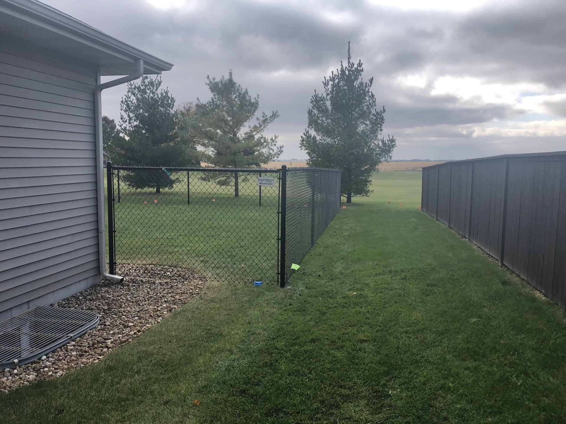 A chain link fence is in the backyard of a house.
