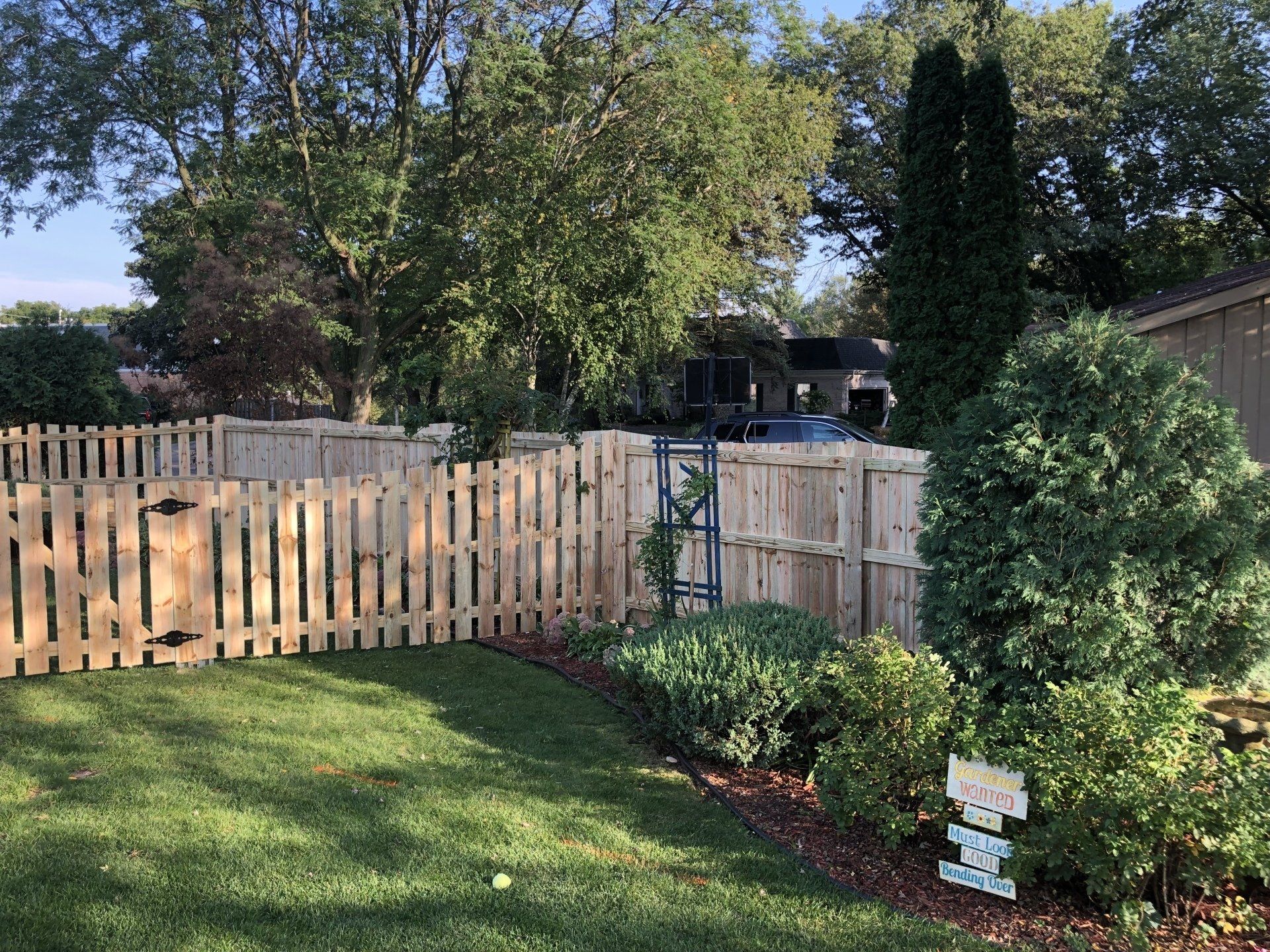 A wooden fence surrounds a lush green yard.