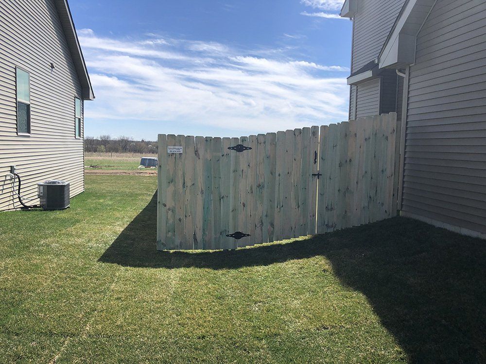 A wooden fence is in the backyard of a house.