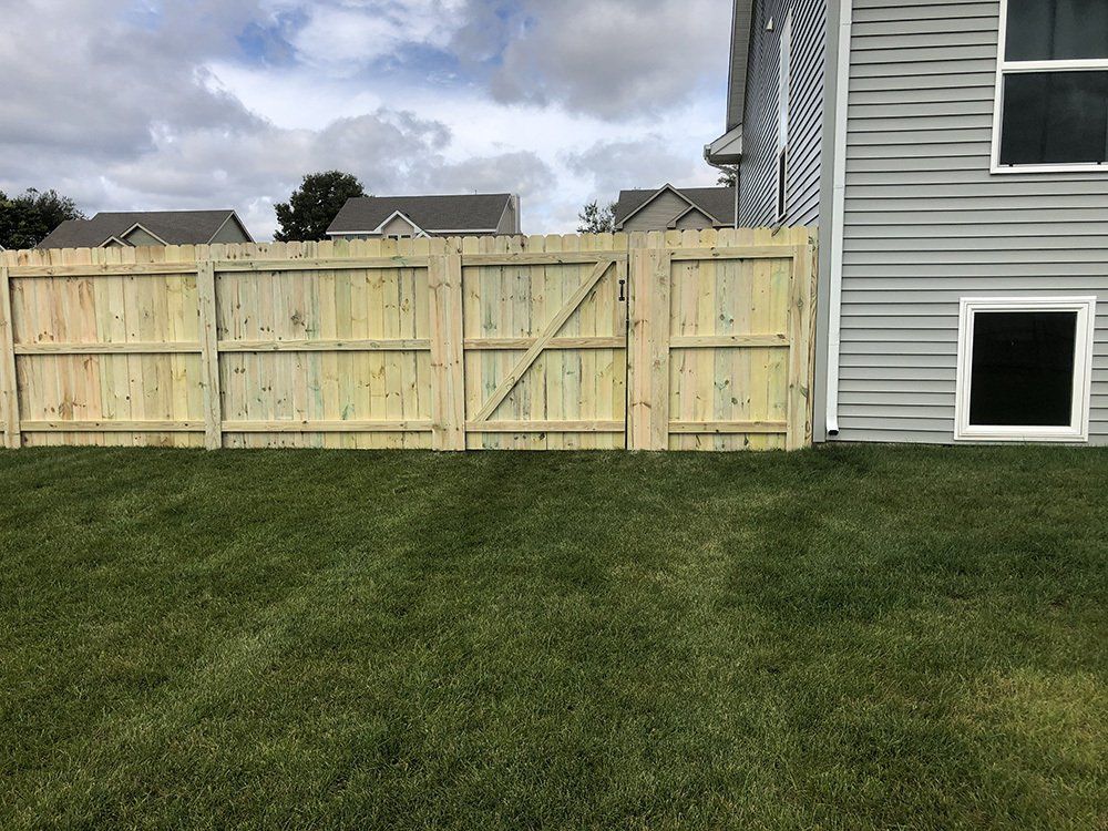 A wooden fence is in the backyard of a house.