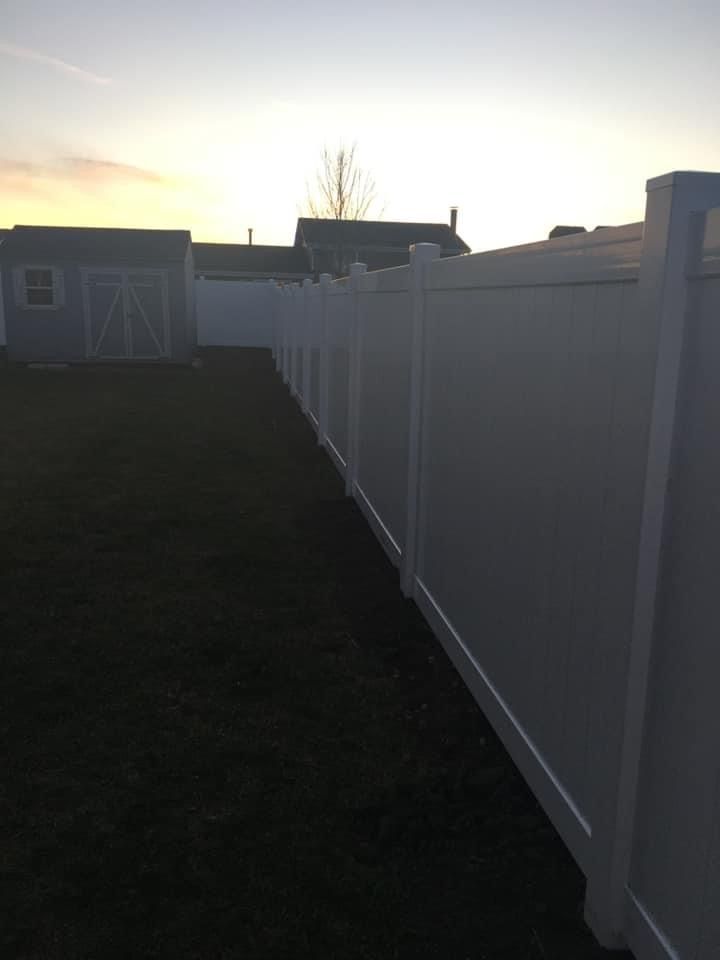 A newly installed white fence in the backyard of a house