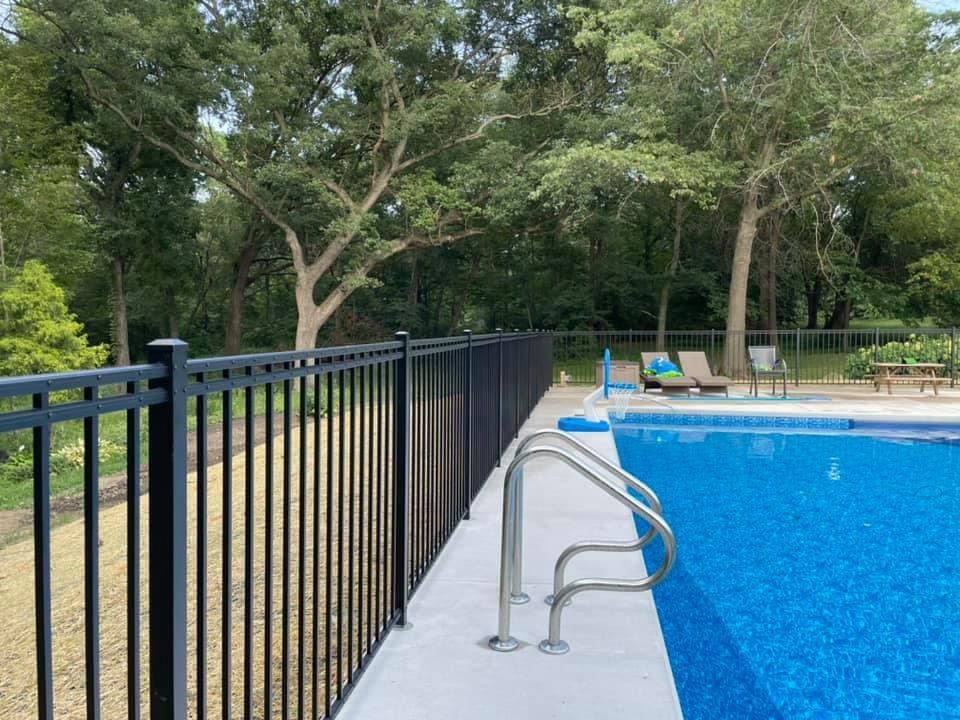 A swimming pool with a newly installed black fence around it