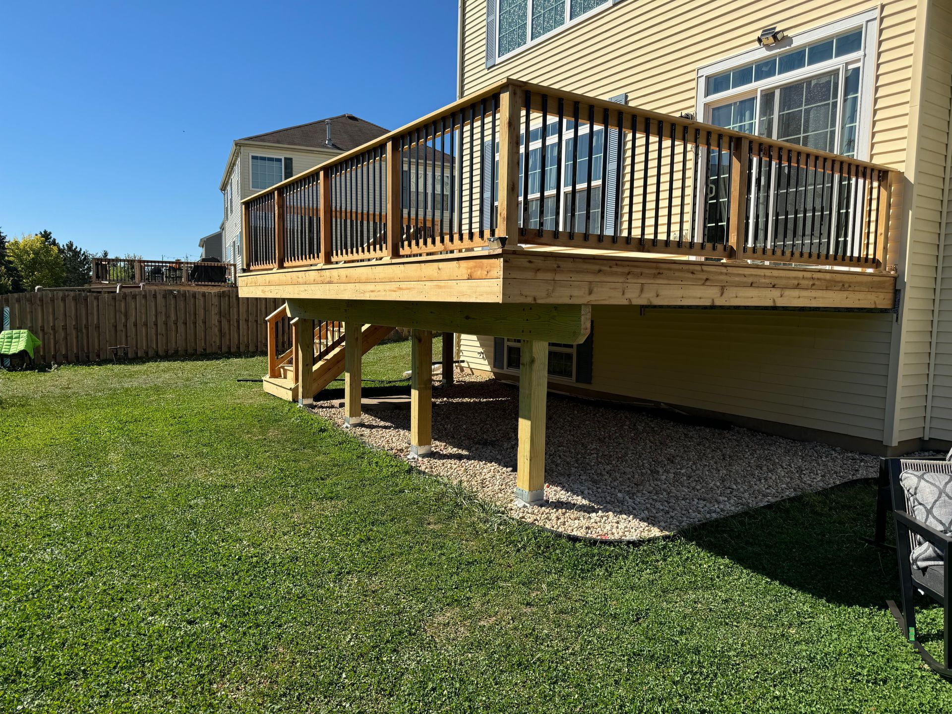 A large wooden deck is in the backyard of a house.