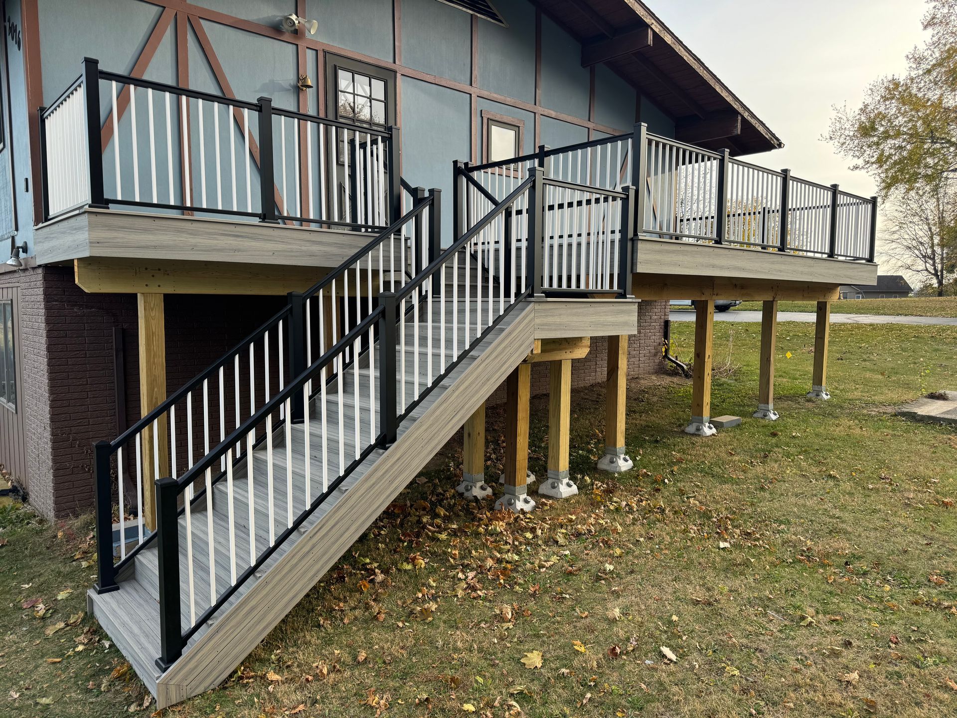 A large deck with stairs leading up to it is in front of a house.